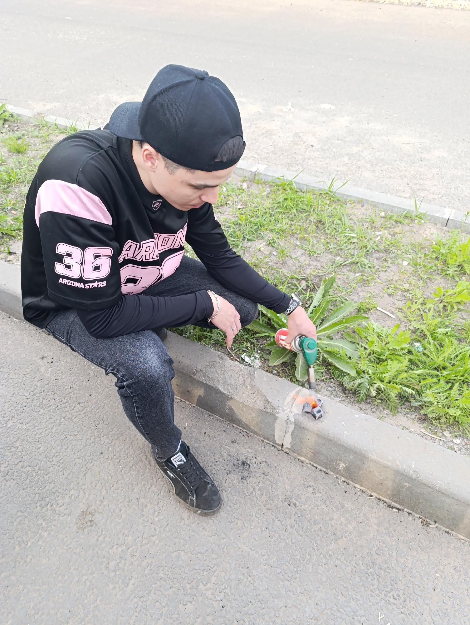 Young man in sports jersey observed cleaning car in urban setting