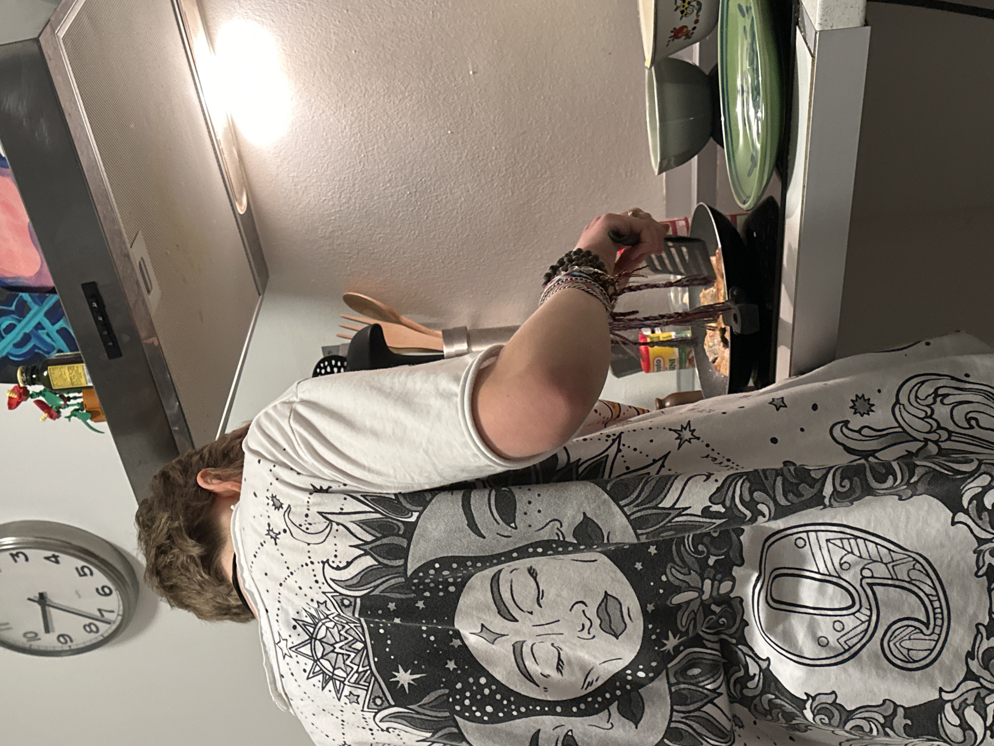 Person cooks dinner in Milan kitchen wearing sun-design shirt