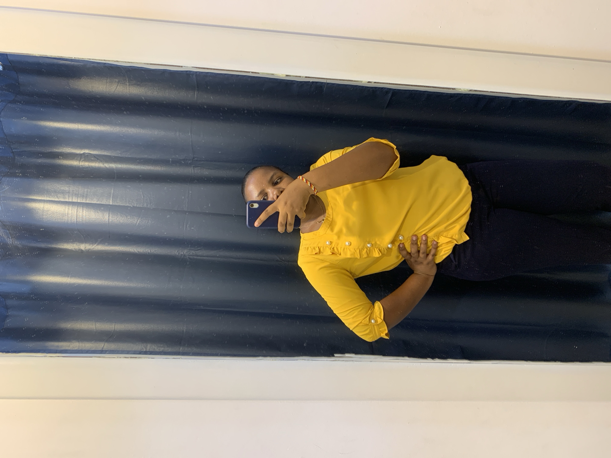Woman takes selfies in yellow blouse at Dar es-Salaam location