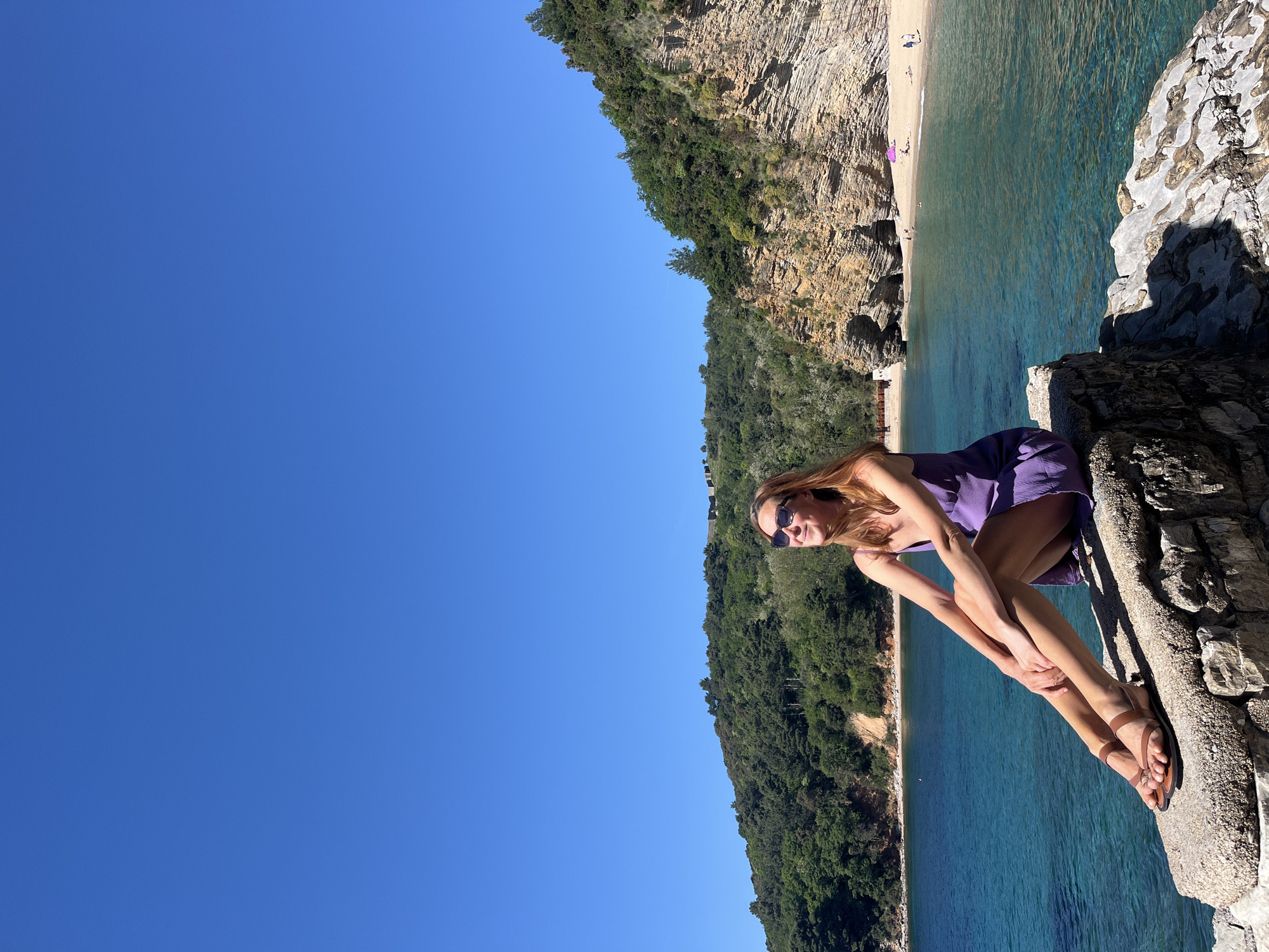 Woman sunbathes on rocky cliffs overlooking Budva beach