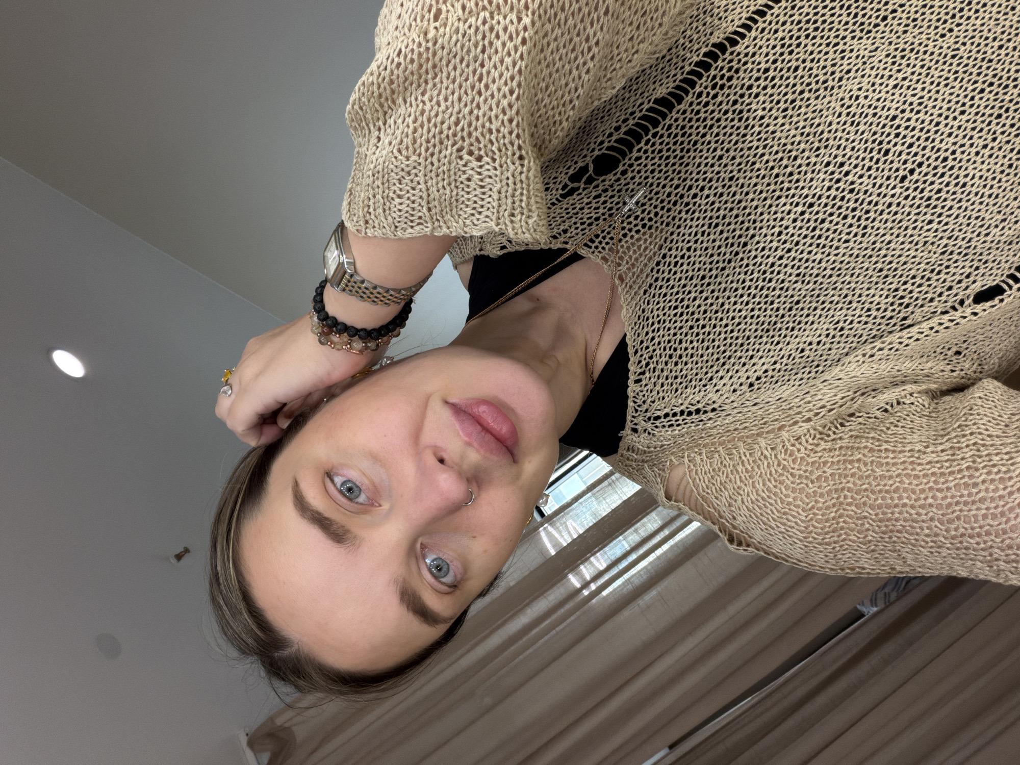Woman in beige sweater observed wearing jewelry accessories