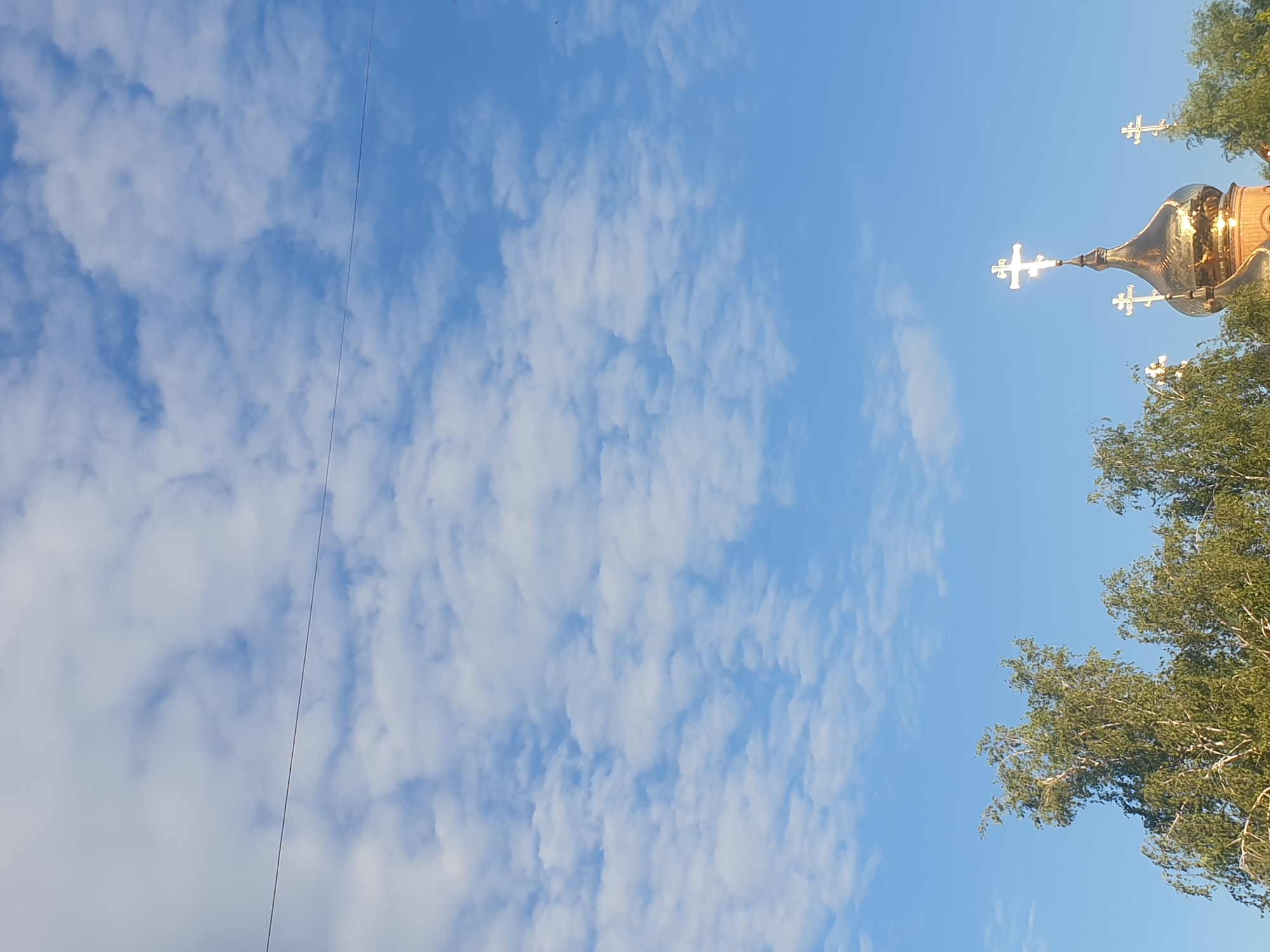 Golden Orthodox church dome glinting above the trees in Obukhiv