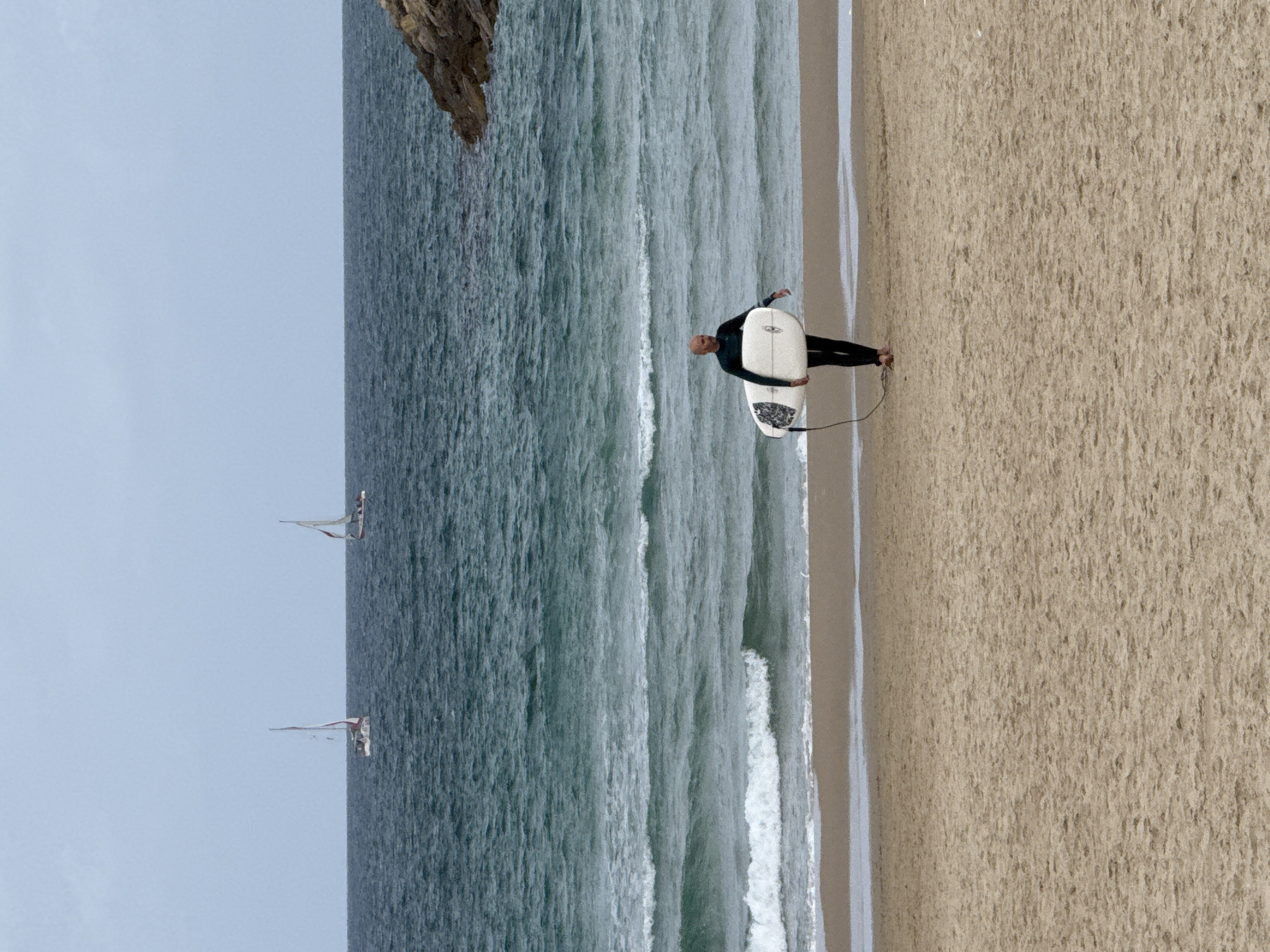 Surfer walks beach with white board in Herzliya