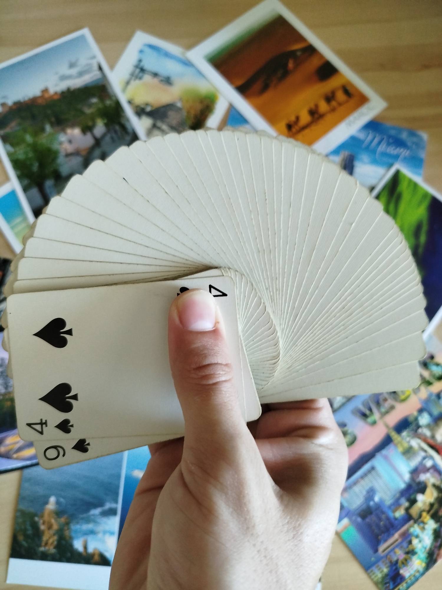 Travel postcards and playing cards spread across a Varna table