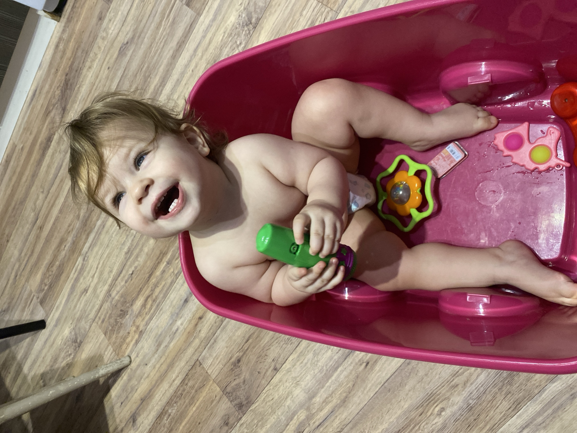 Toddler enjoys bath time with colorful toys