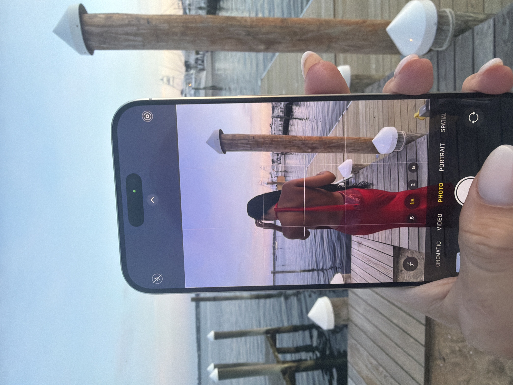 Golden hour on a Montauk dock, phone out, water still.