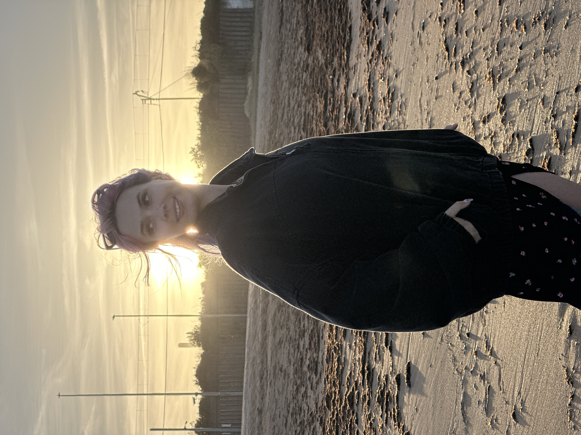 Purple-haired woman enjoys sunset beach walk with dog in Gijón