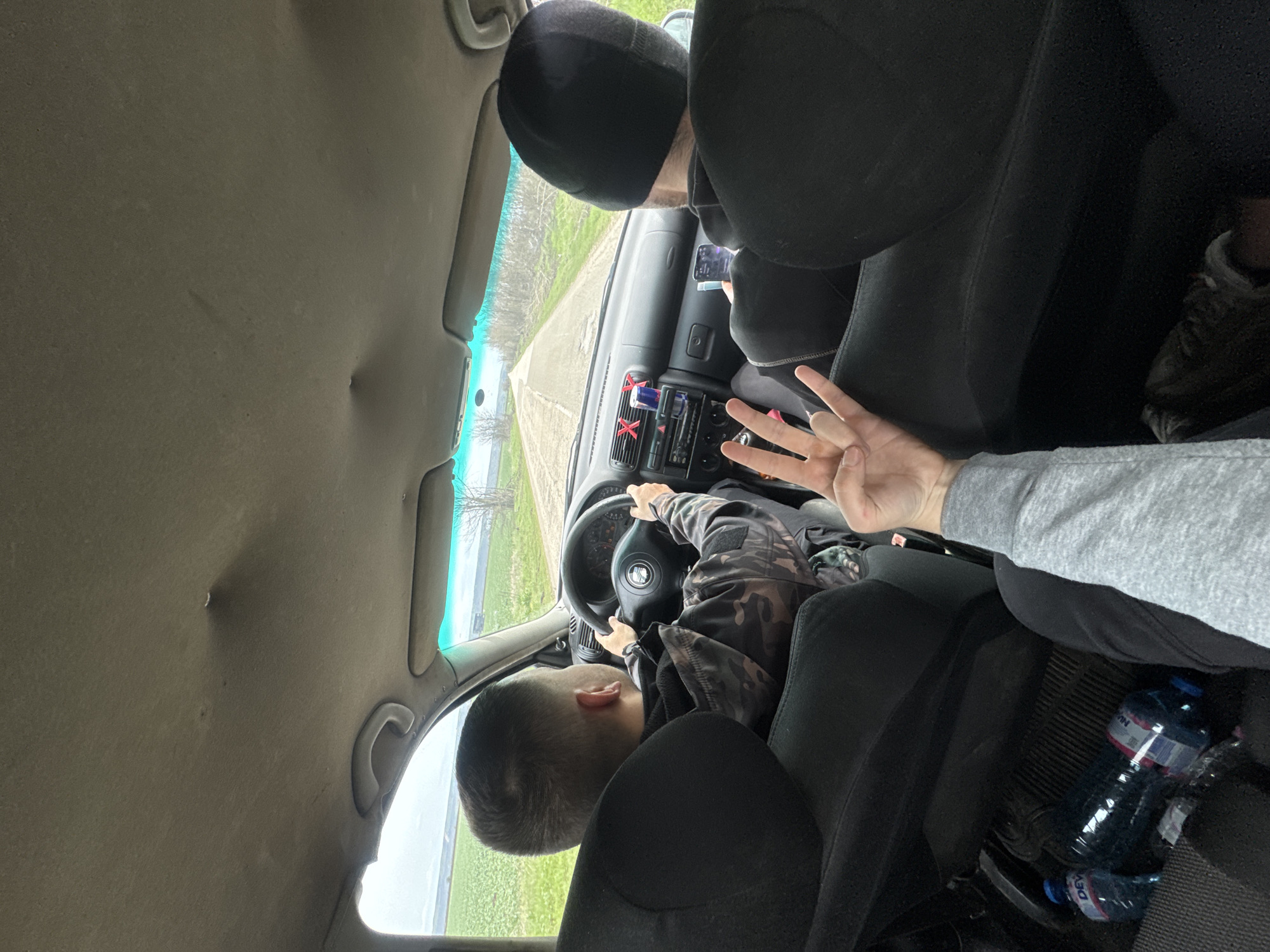 Child sits in driver's seat with adult passenger