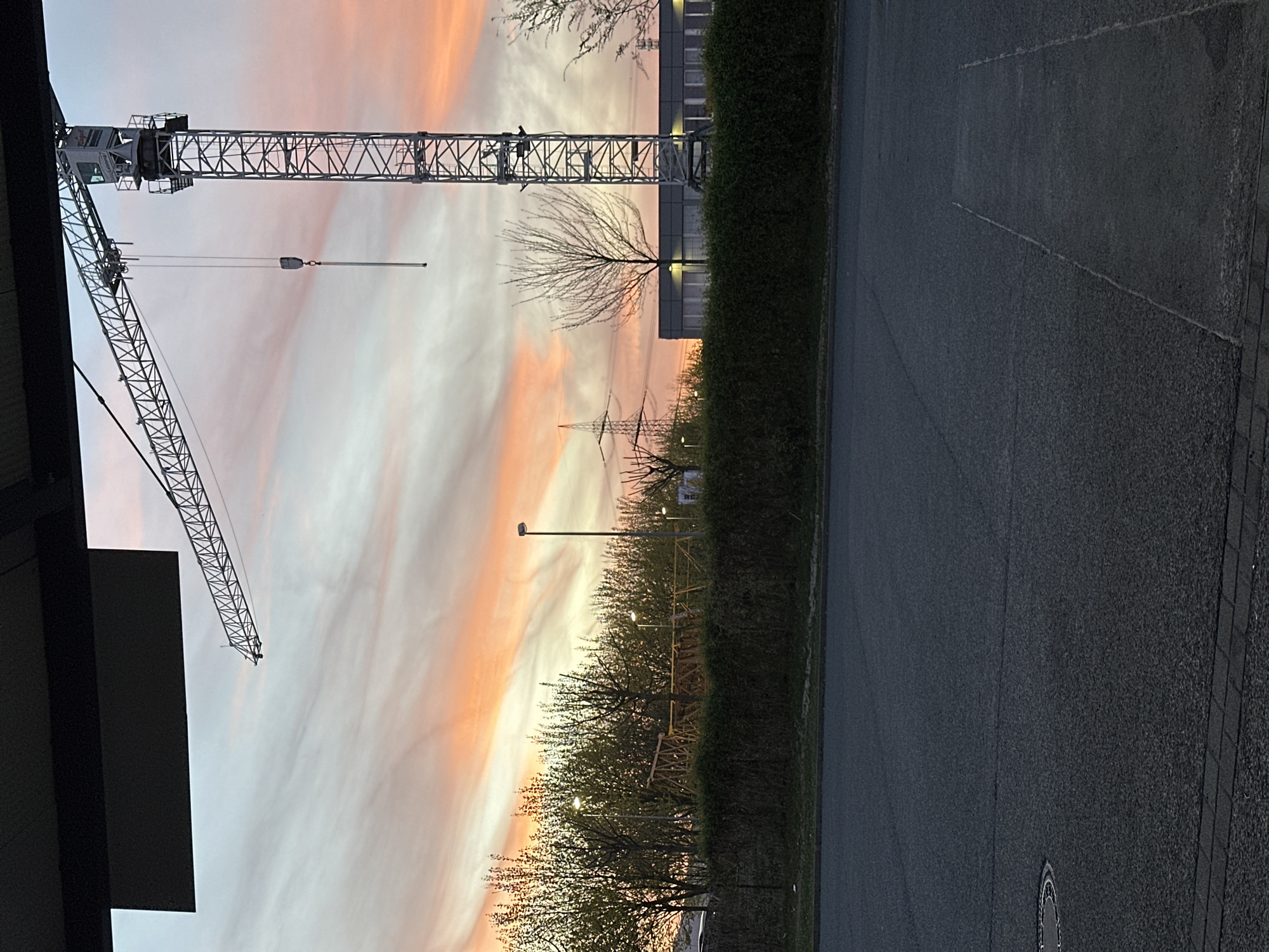 Construction crane silhouetted against vibrant sunset in Frankfurt