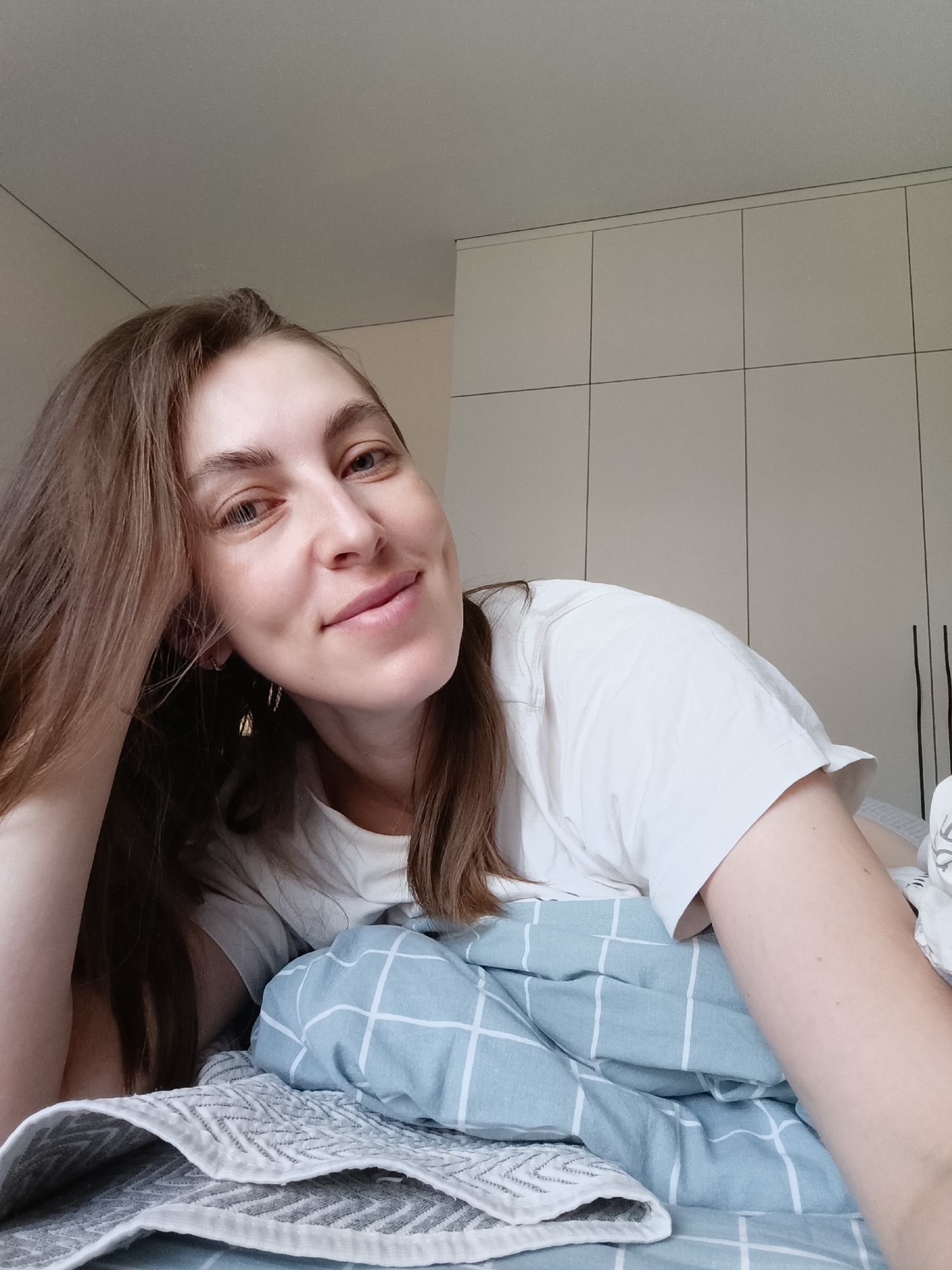 Woman rests in bed as cat sits by window in Chaikovsky