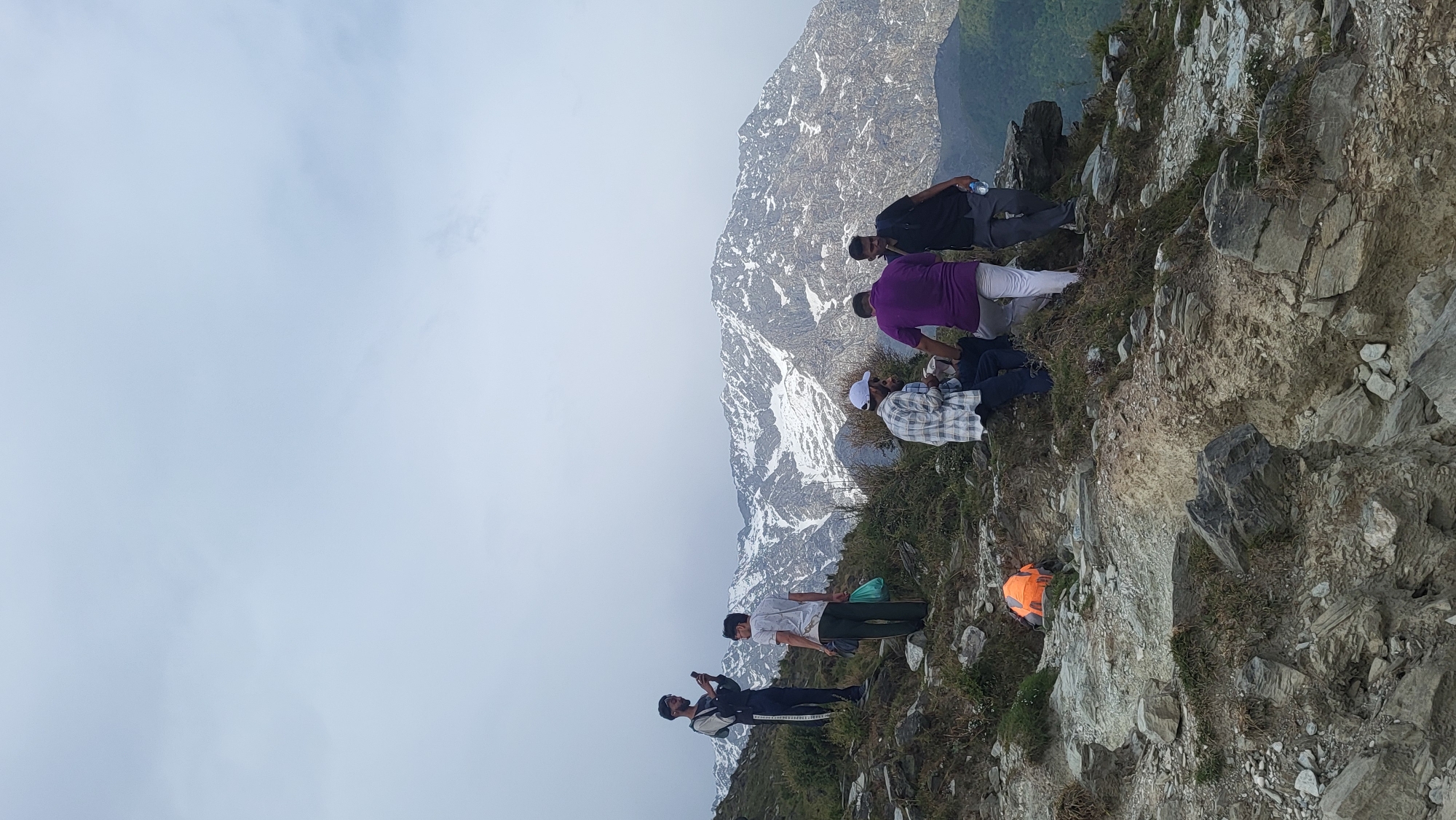 Hikers traverse rocky trail near Dharamshala amid overcast skies