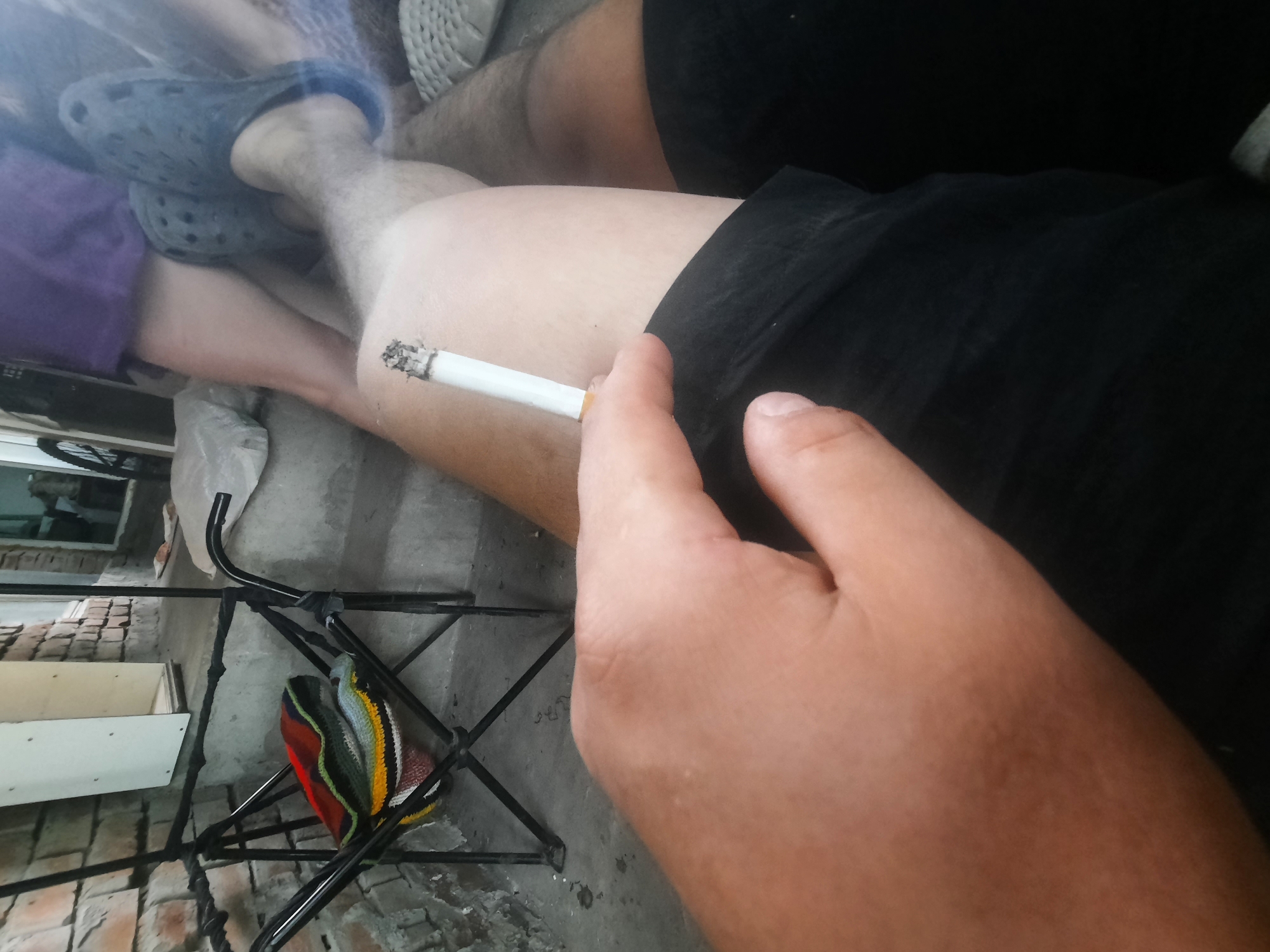 Person photographed smoking cigarette while seated in casual attire