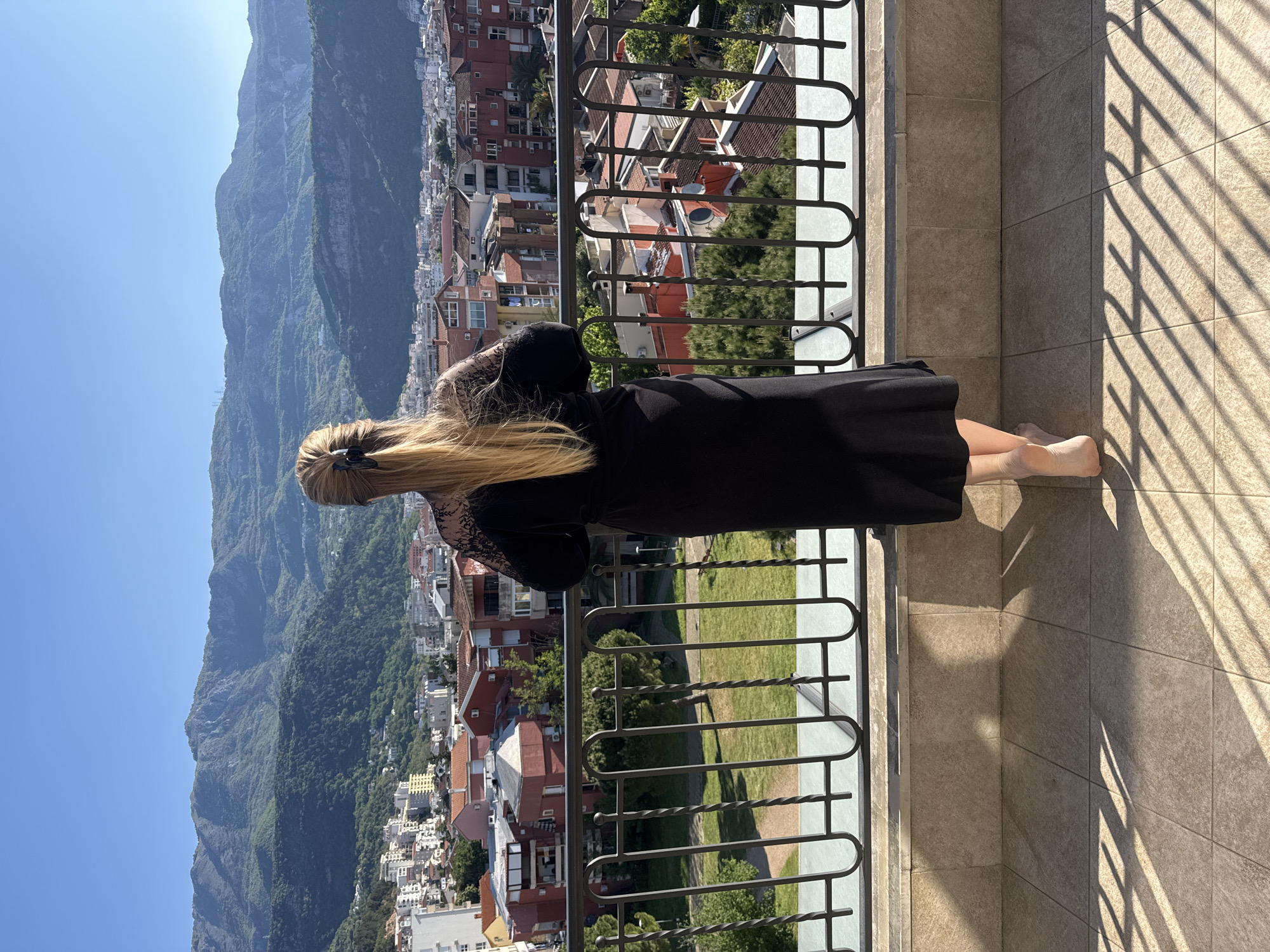 Woman in black dress observed on Budva balcony overlooking mountains