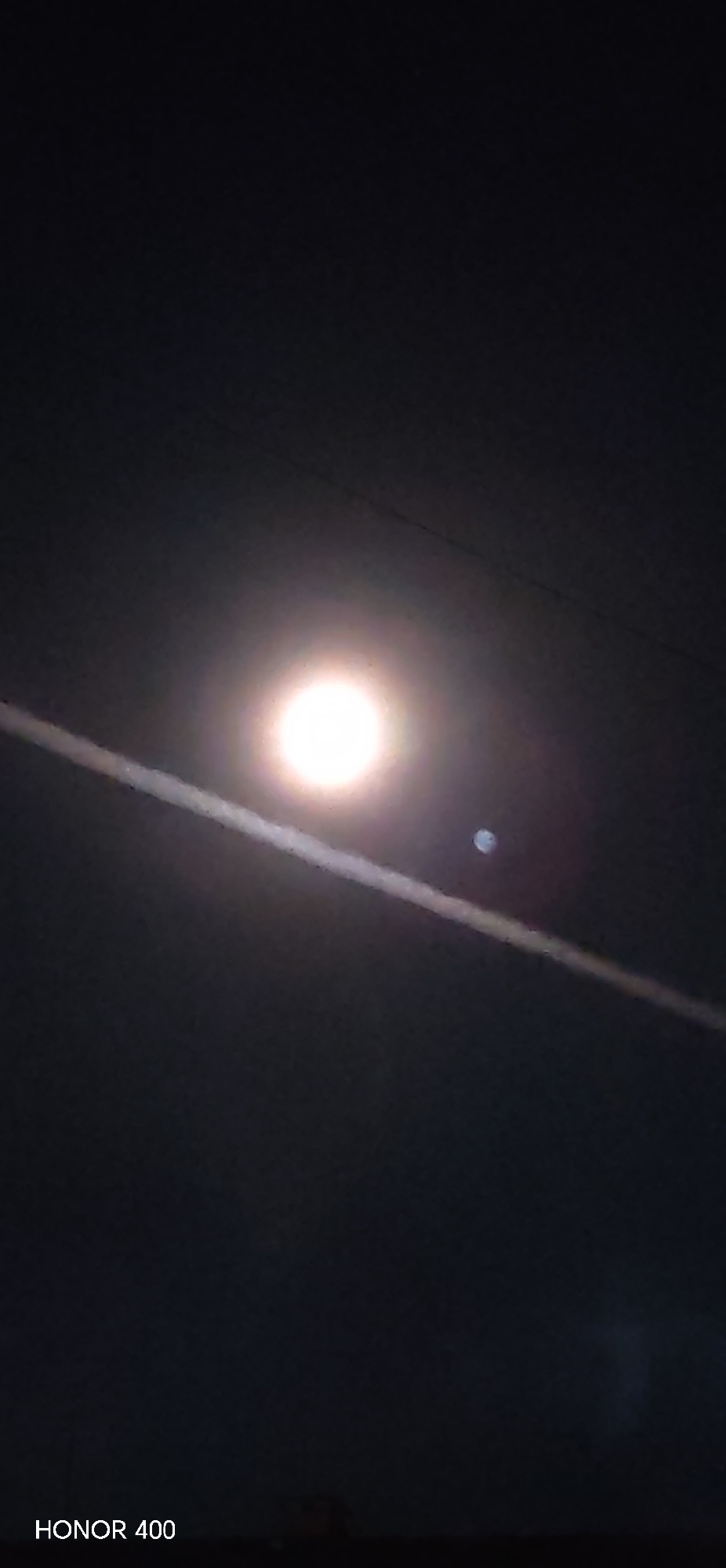 Moon and contrail photographed over Russian residential buildings