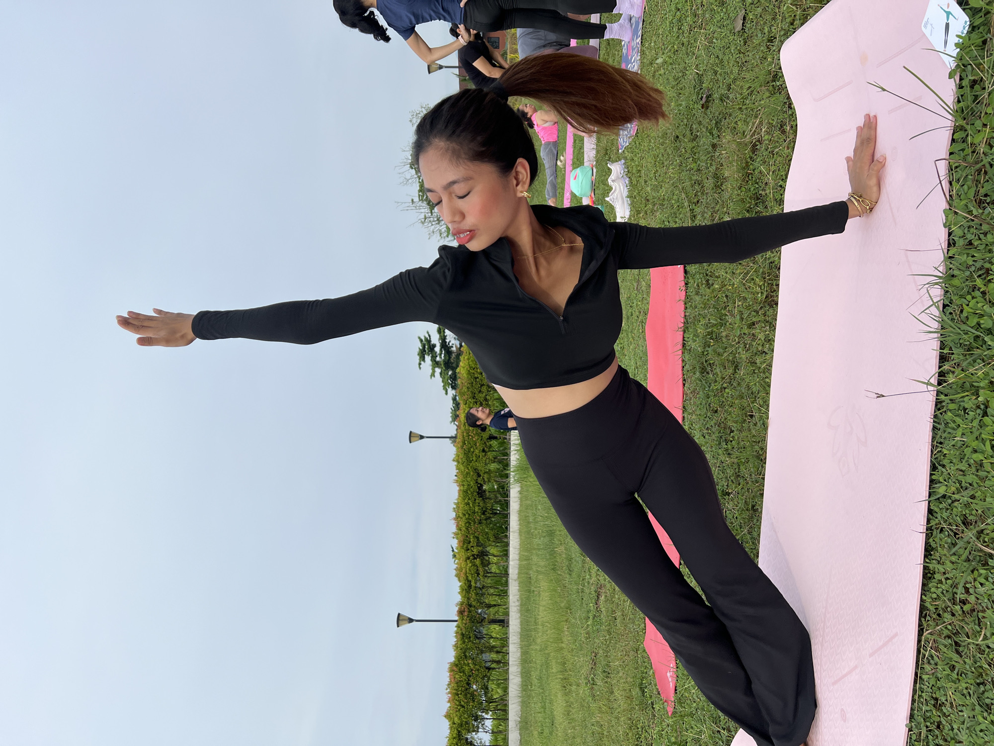 Outdoor group yoga session on a grassy field in Davao City