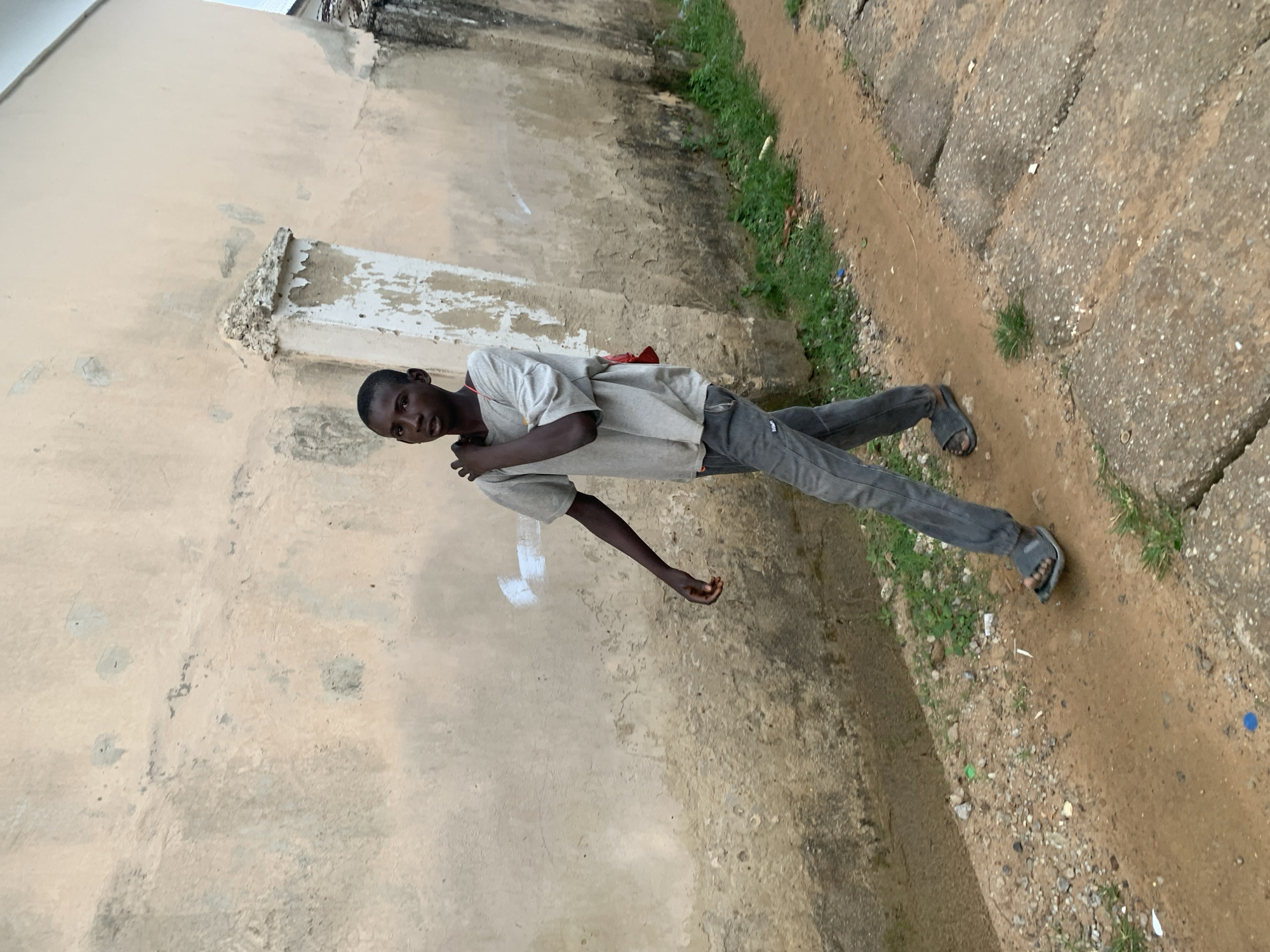 Morning foot traffic along a walled pathway in Abuja