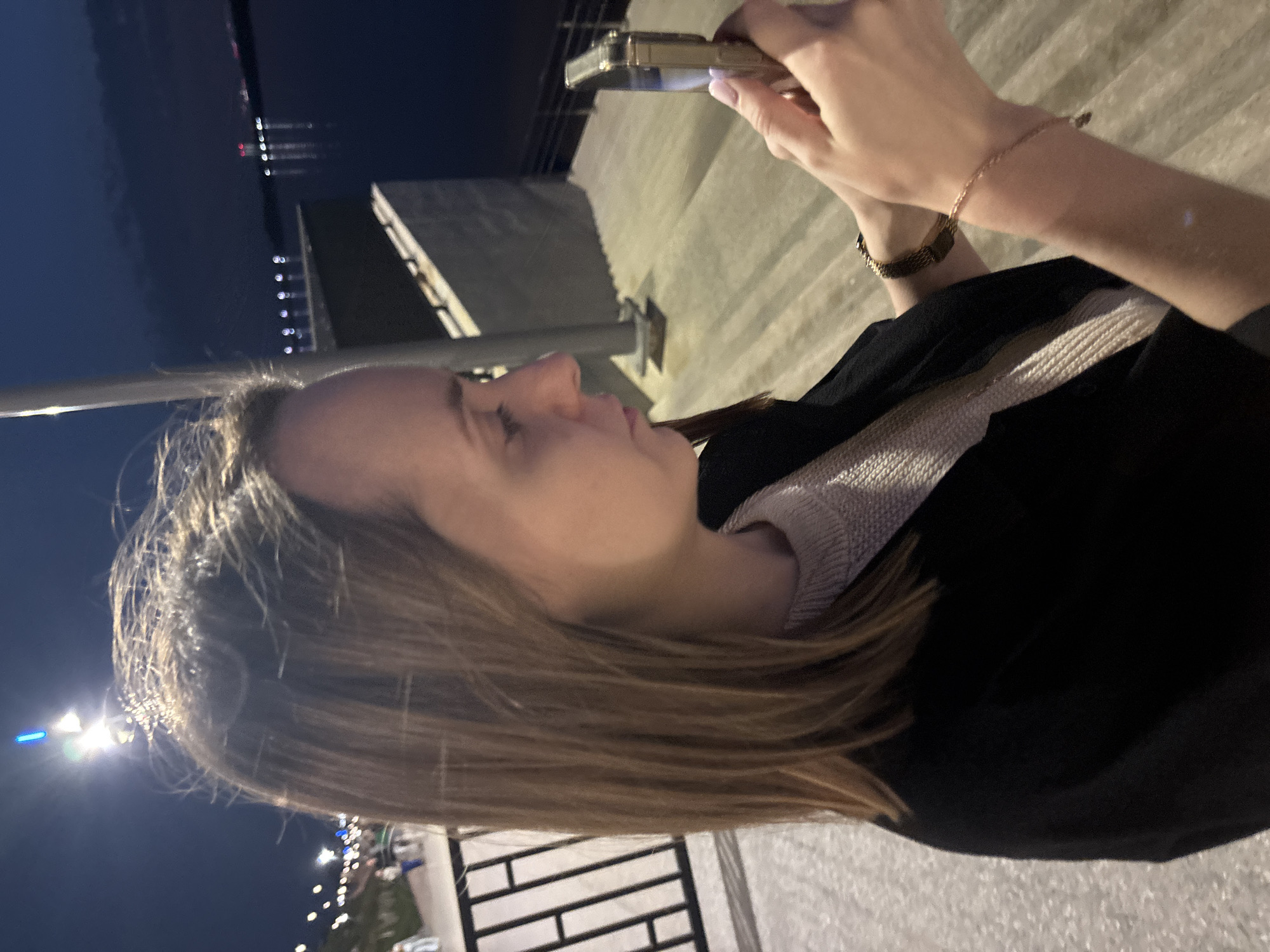 Woman uses phone at Perm waterfront during evening hours