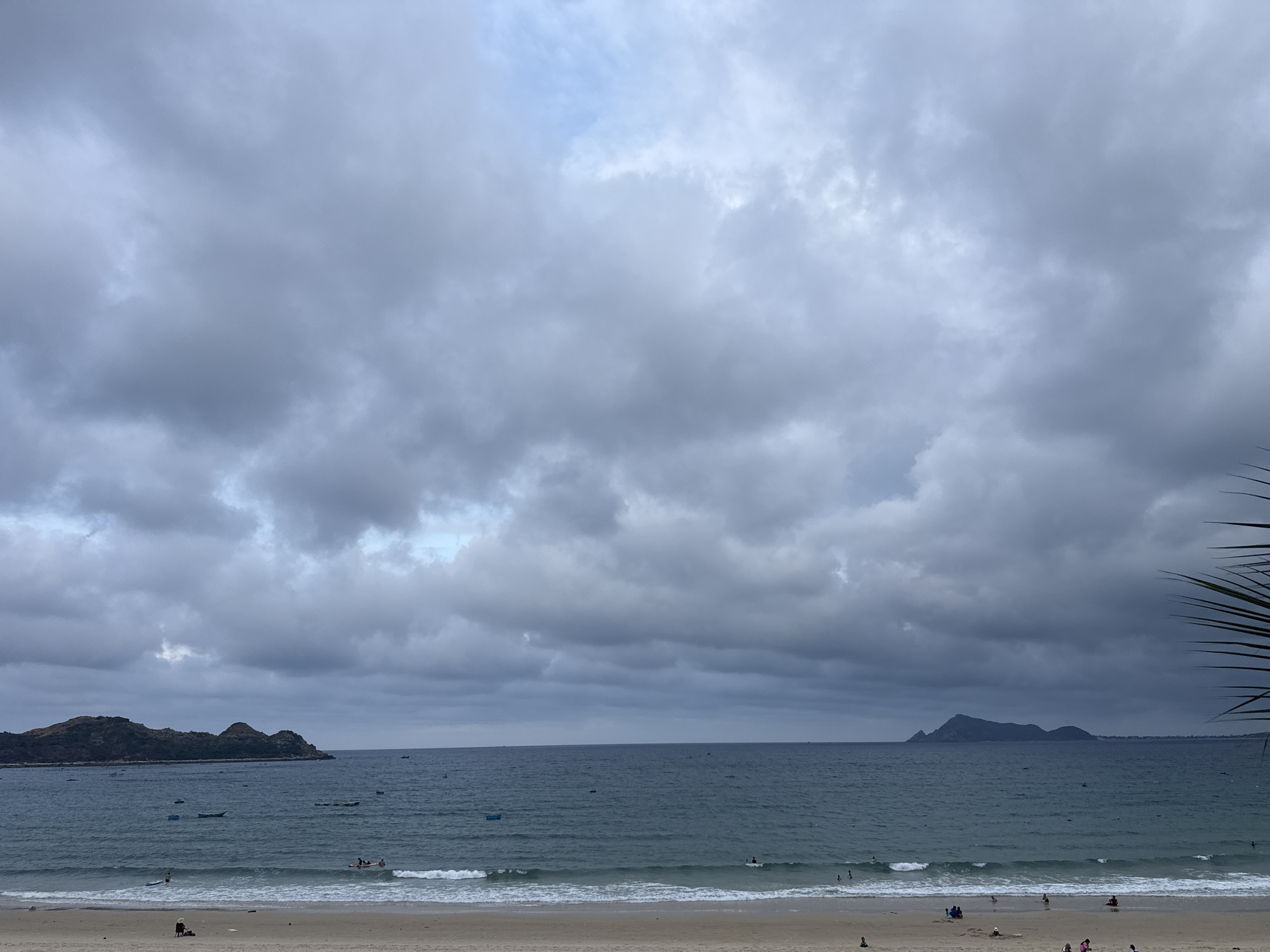 Quiet tropical beach, overcast morning, boats dotting calm water