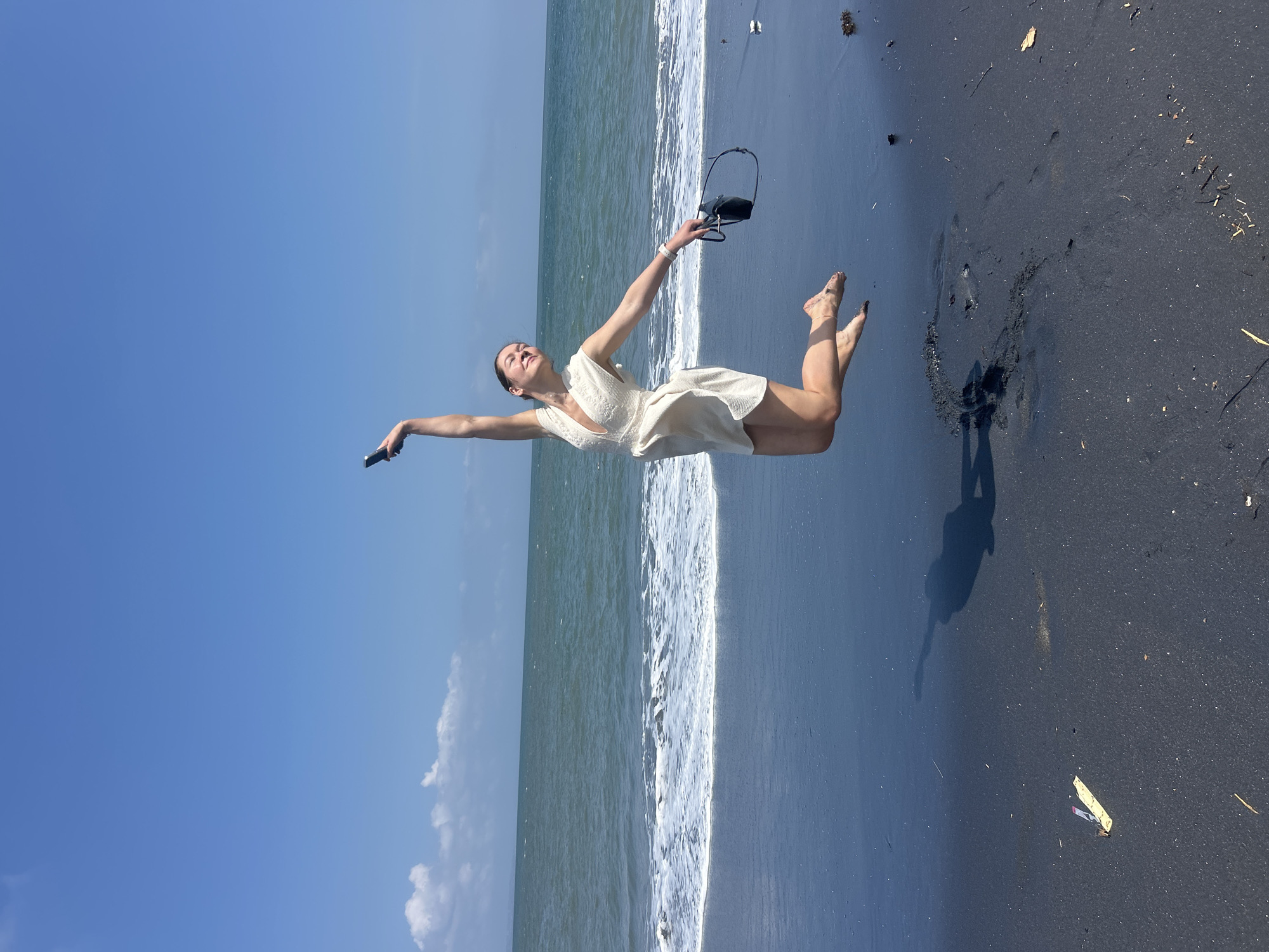 Jumping and posing on a black sand beach in Mengwi