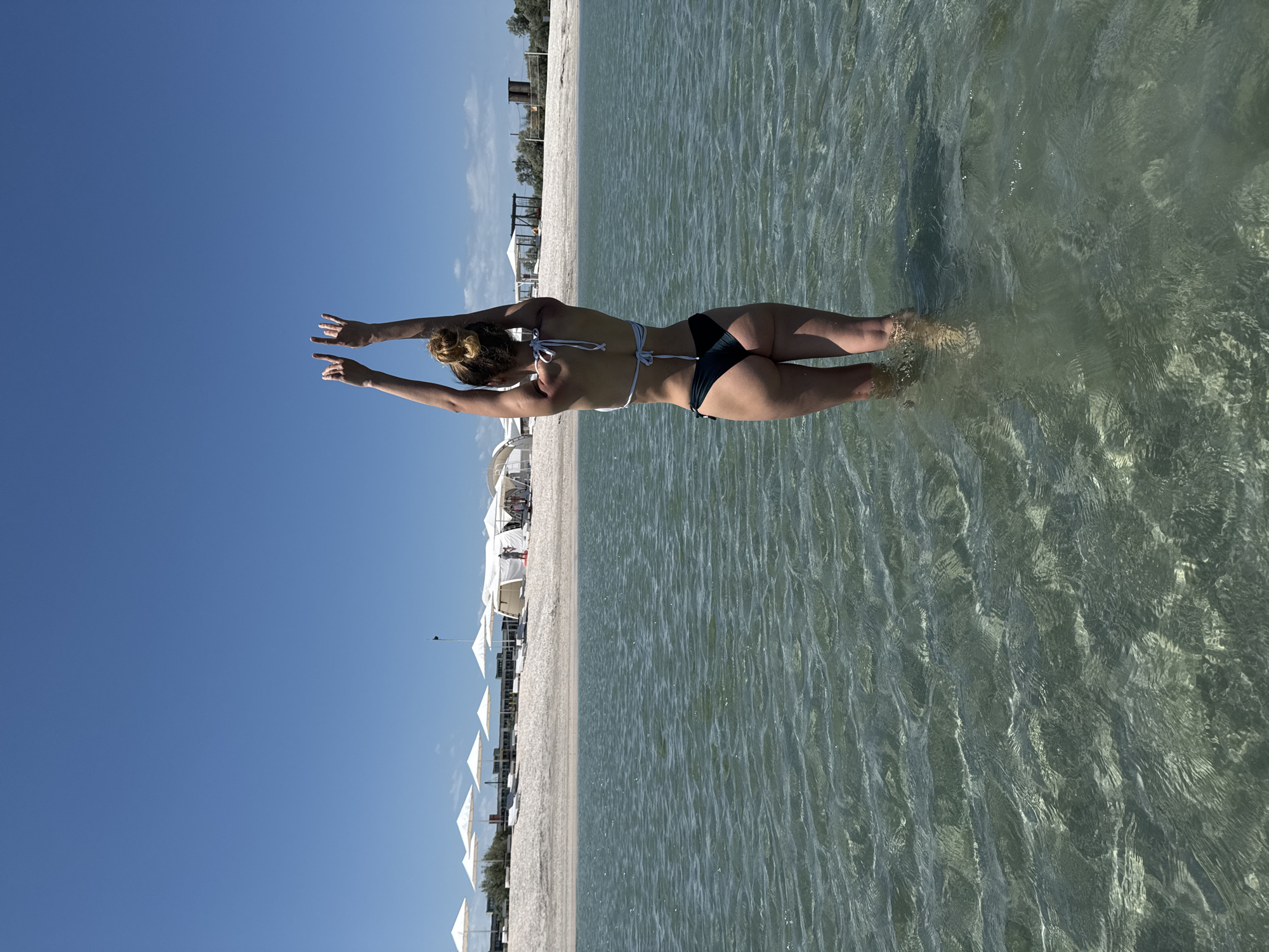 Woman swimming and sunbathing at unidentified beach location