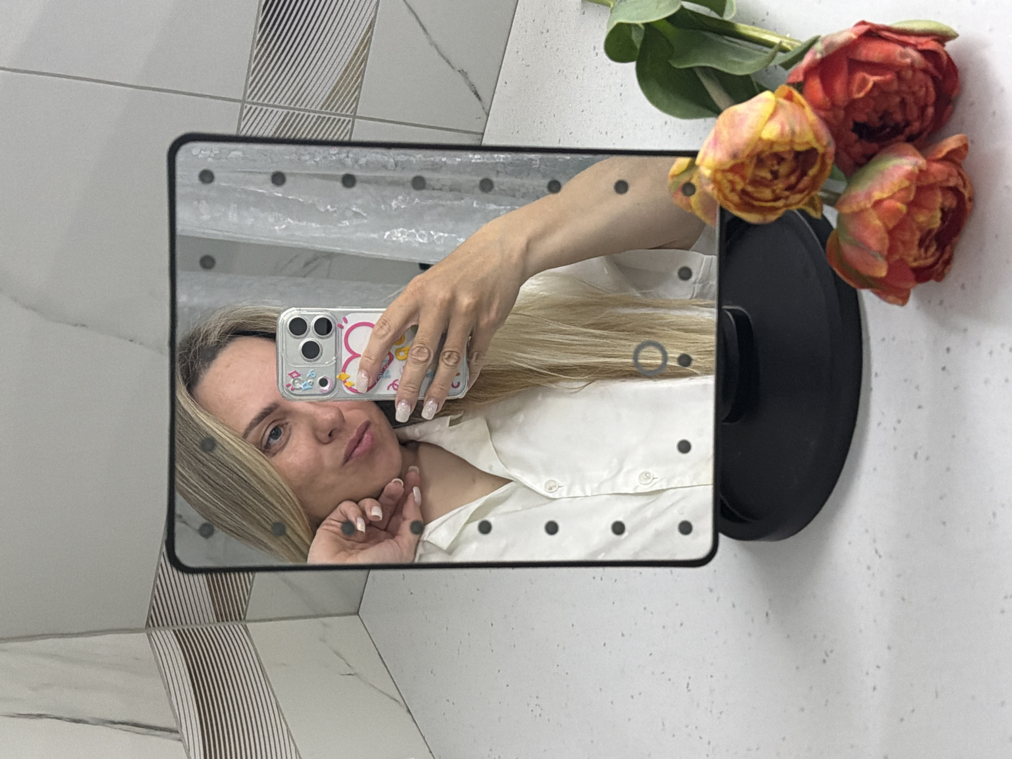 Woman takes bathroom mirror selfies with orange flowers in Votkinsk