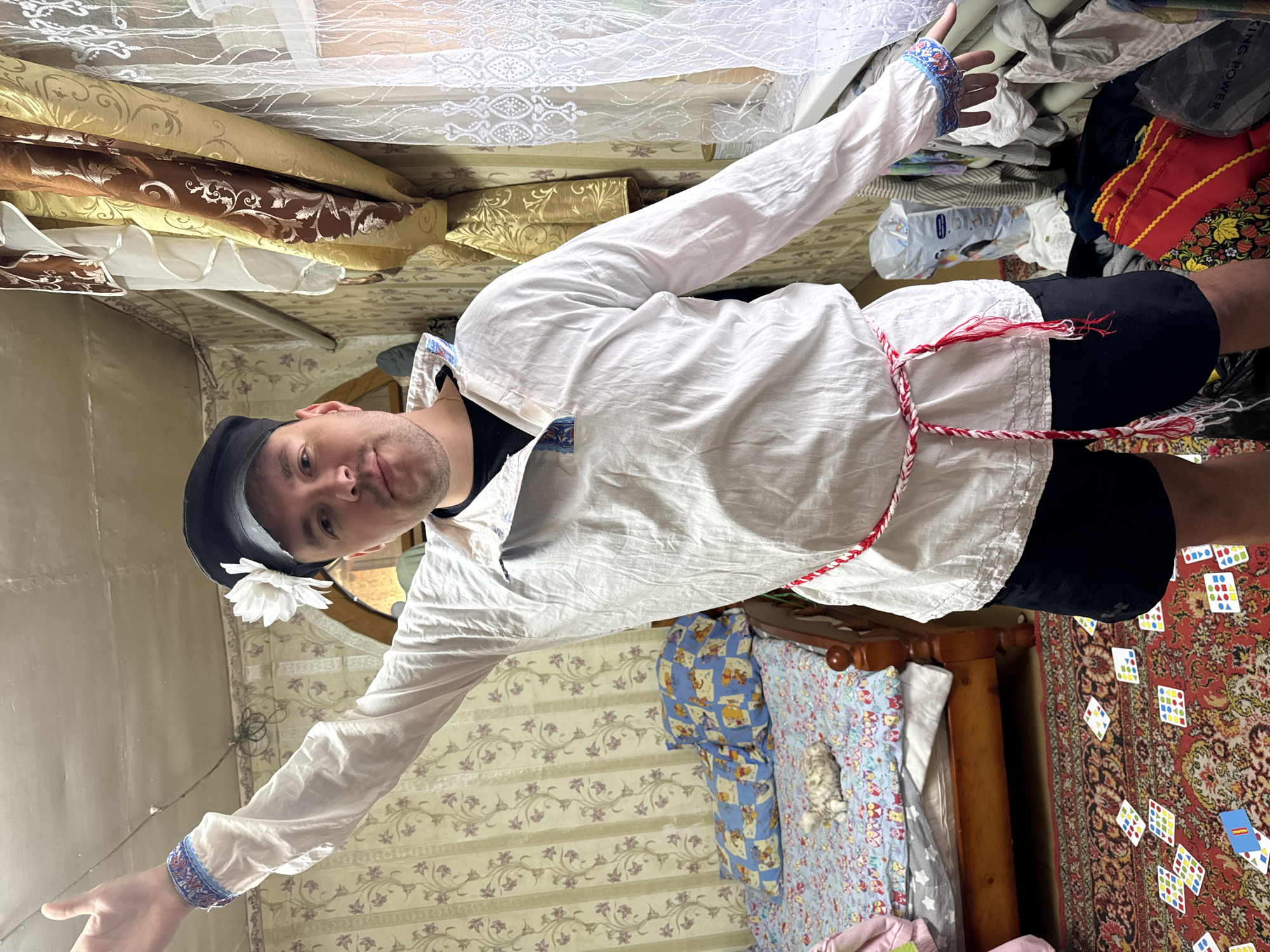 Person stands arms outstretched in cluttered room