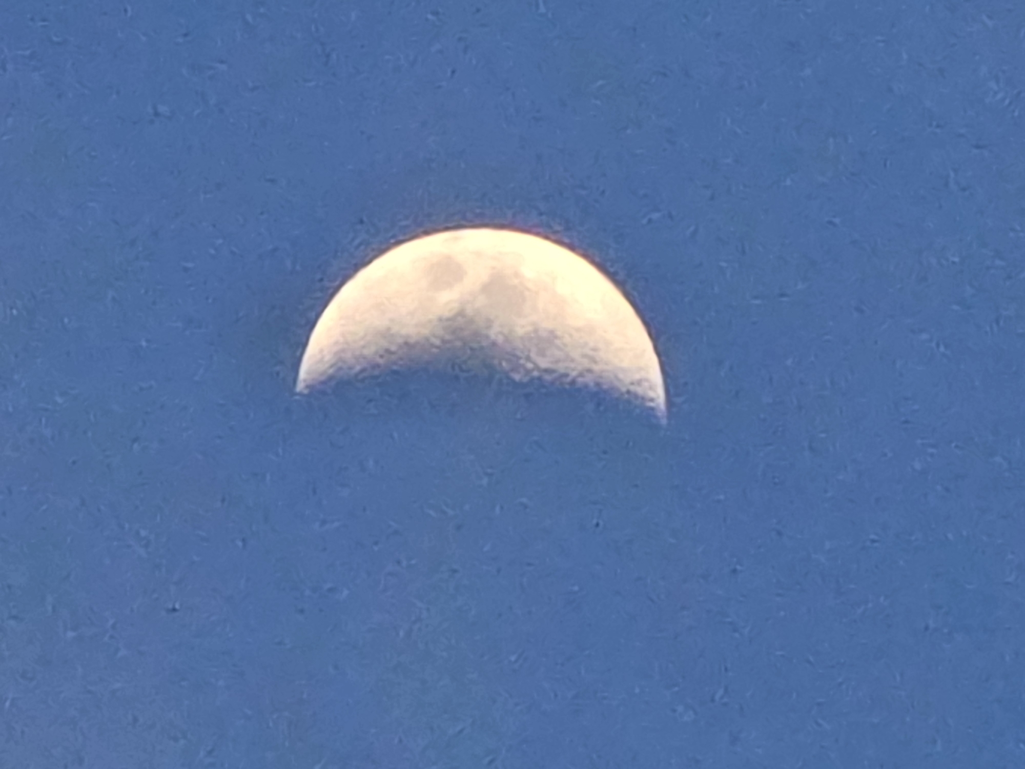 Dusk along a river dam, crescent moon rising overhead