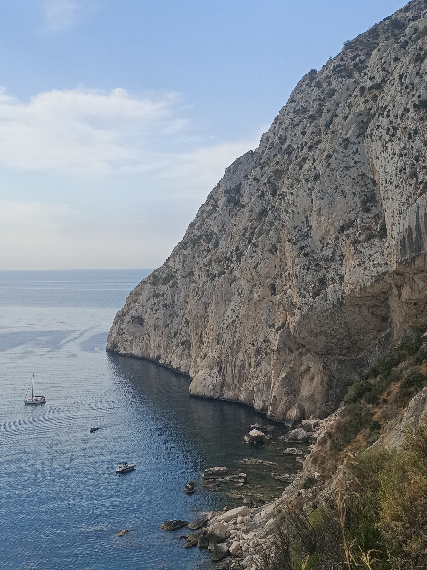 Sheer coastal cliff face meets the sea from above