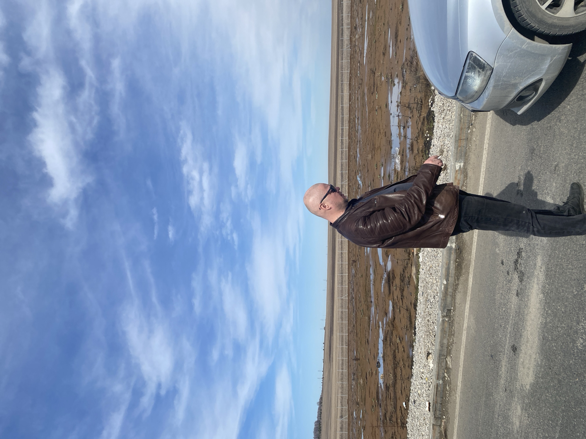 Man in leather jacket stops beside car in rural Russia