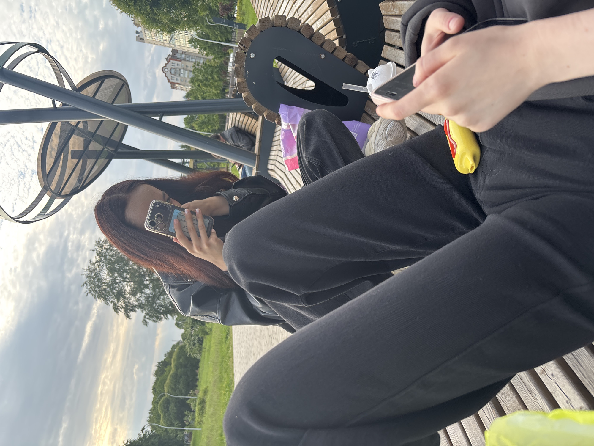 Two women take selfies on park bench in Sinyavino