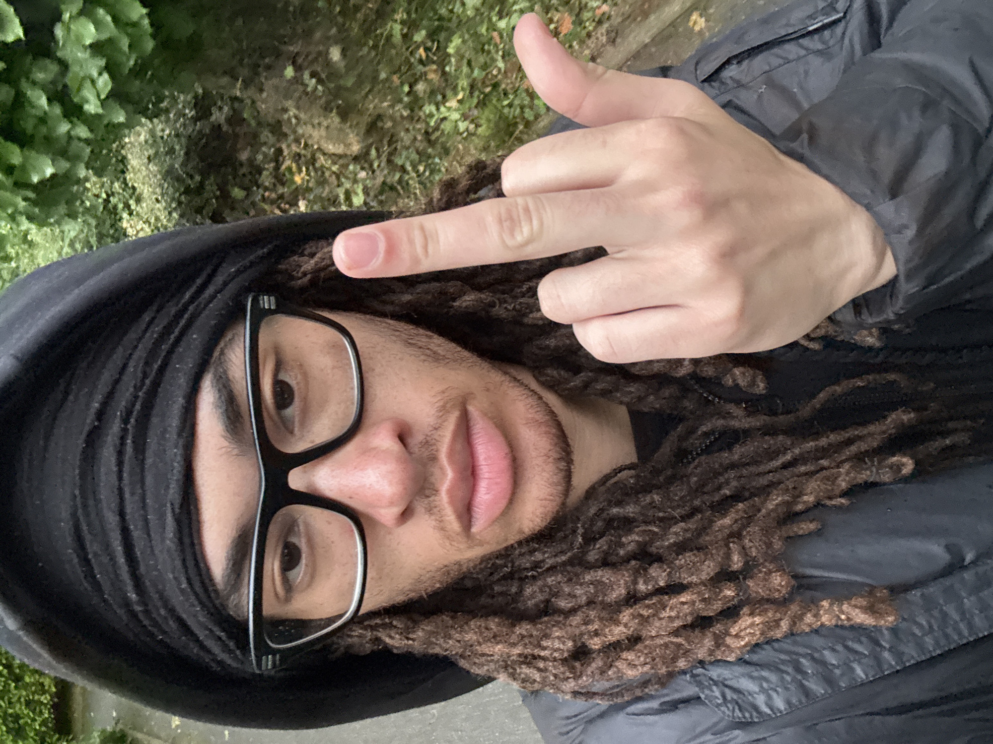 Person with dreadlocks photographed gesturing in Les Ulis park