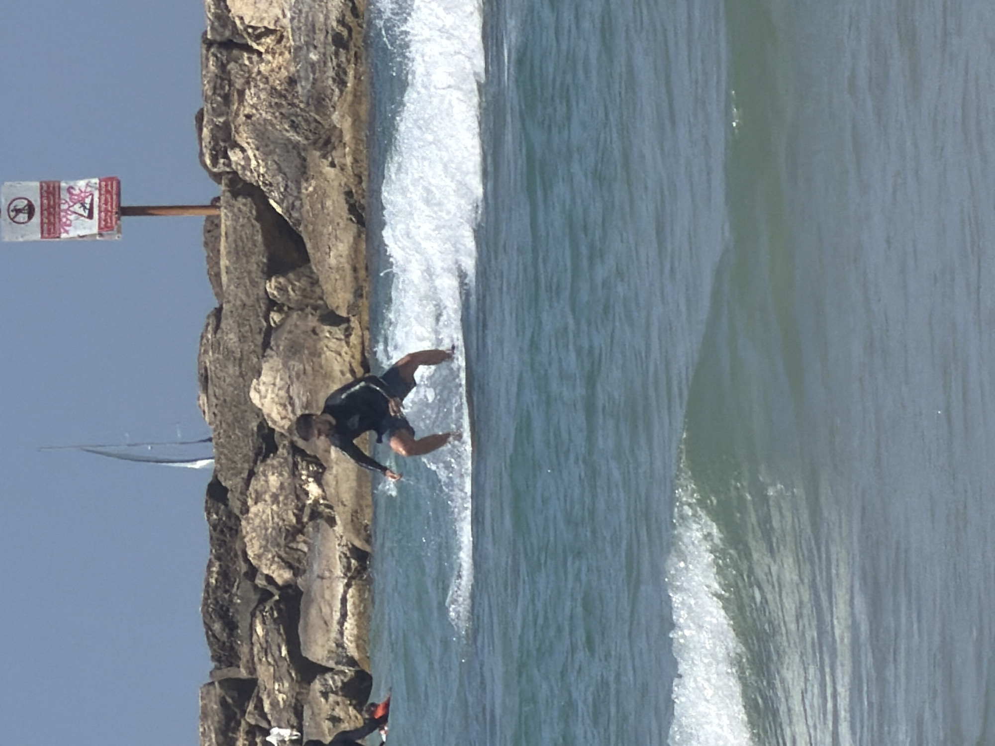 Surfer rides waves near Tel Aviv breakwater