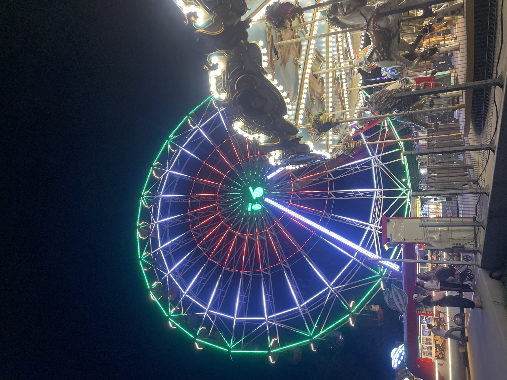 Lit-up Ferris wheel and carousel at a Russian amusement park