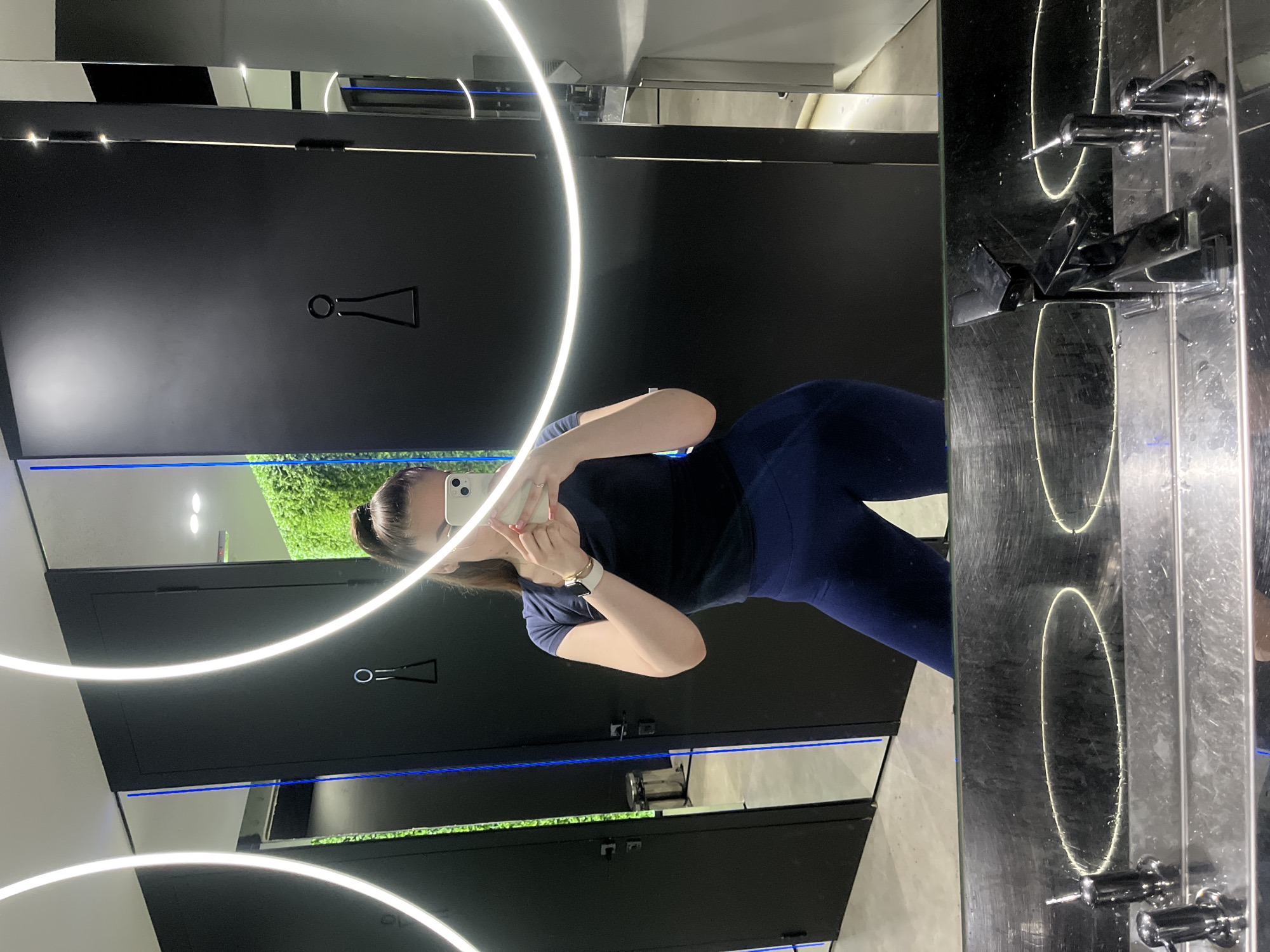 Woman takes selfies in dark mirrored indoor space