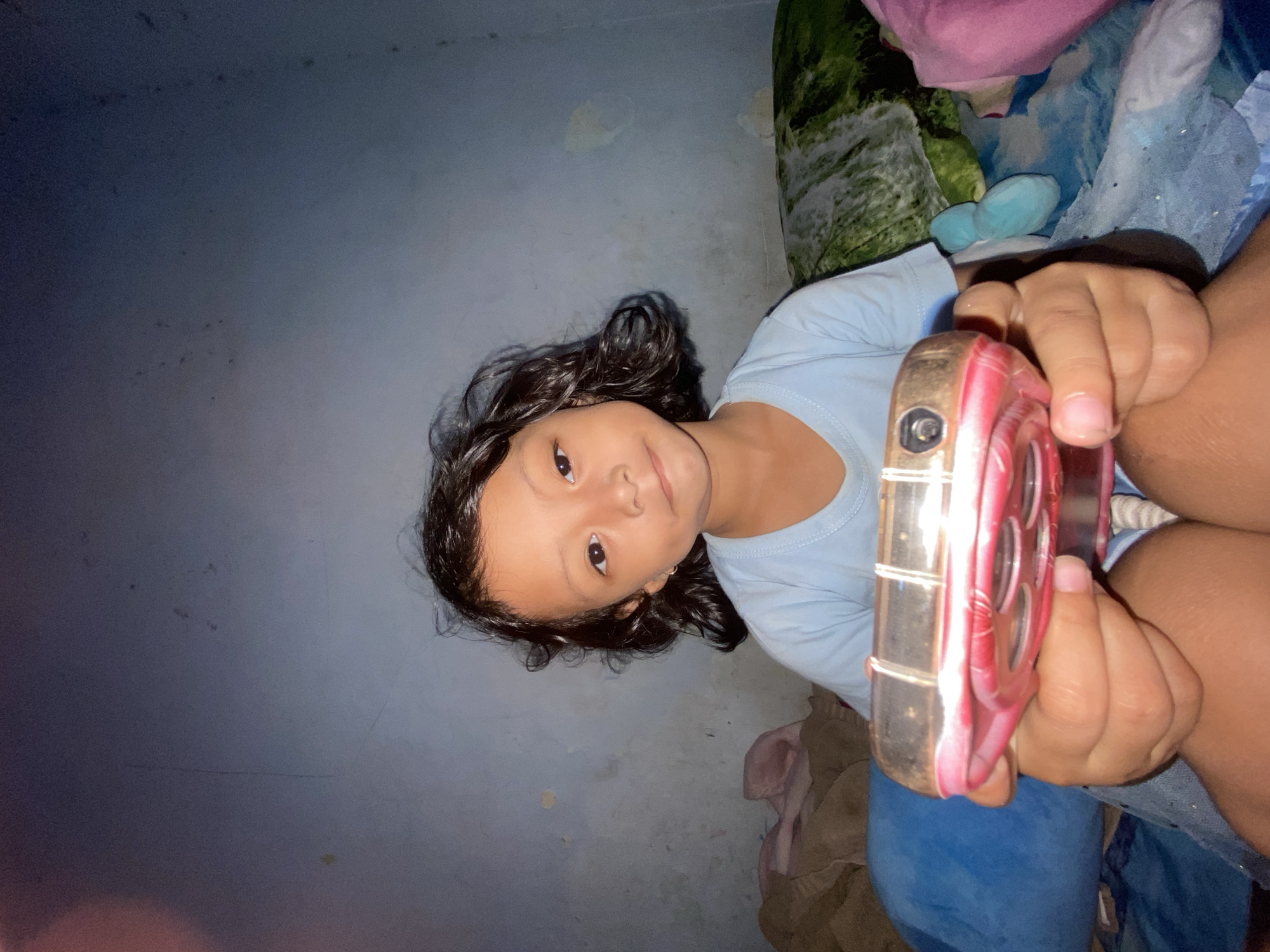 Child displays toy object indoors in Gelam, Indonesia
