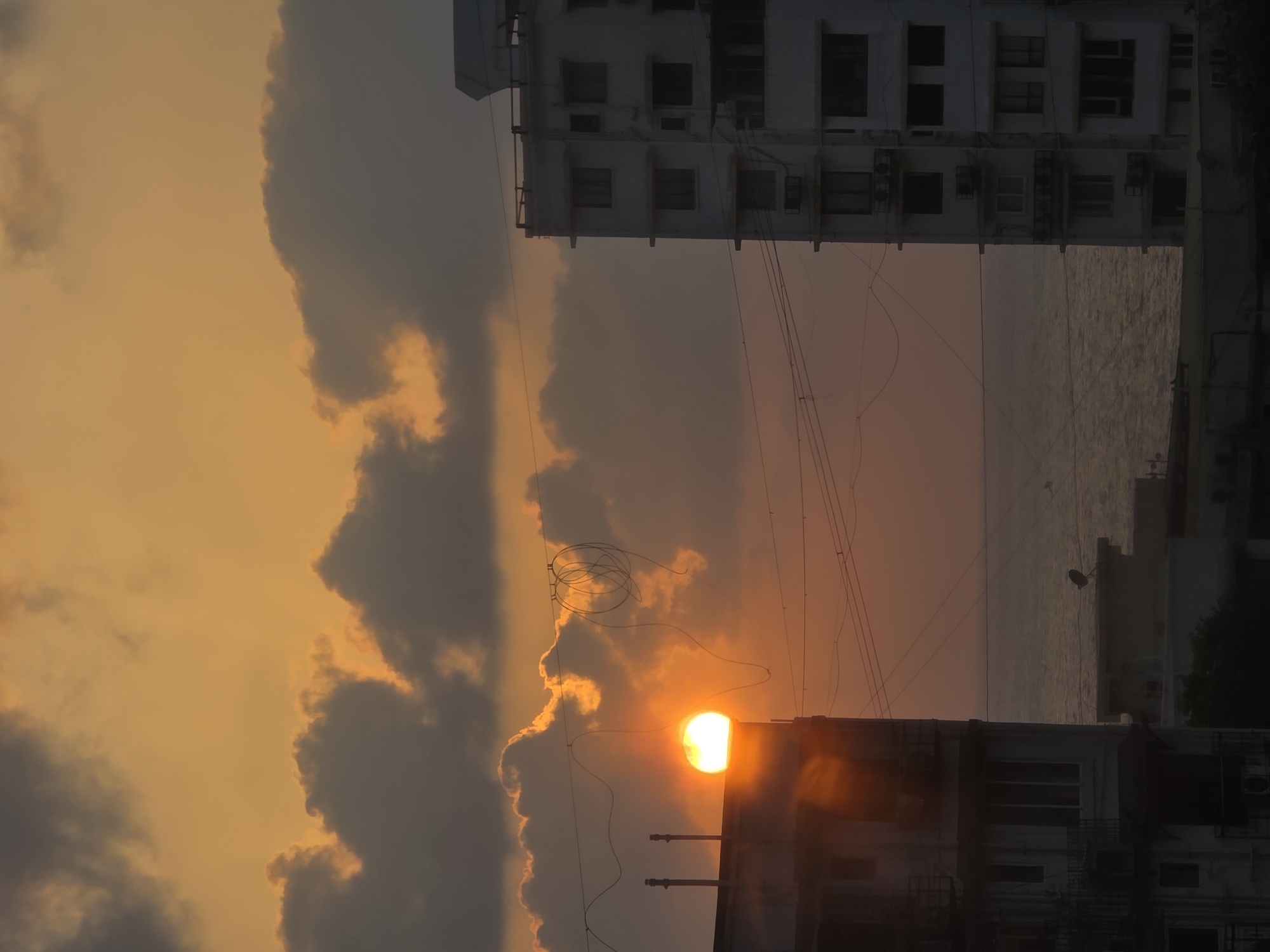 Sunset observed over Mumbai skyline with orange light through clouds