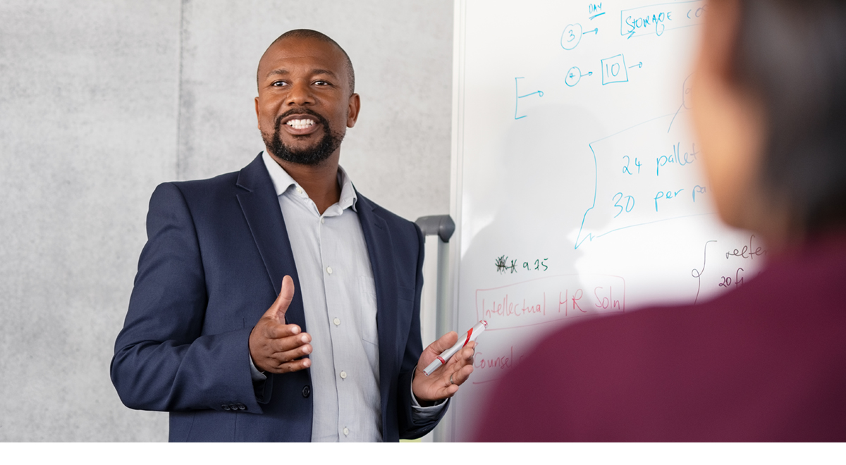 Business manager presenting to their colleagues in front of a white board