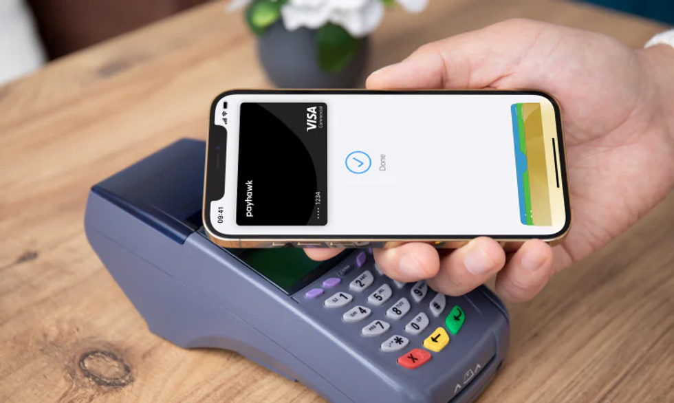 Tarjeta visa corporativa de Payhawk y Apple Pay utilizada en una terminal POS