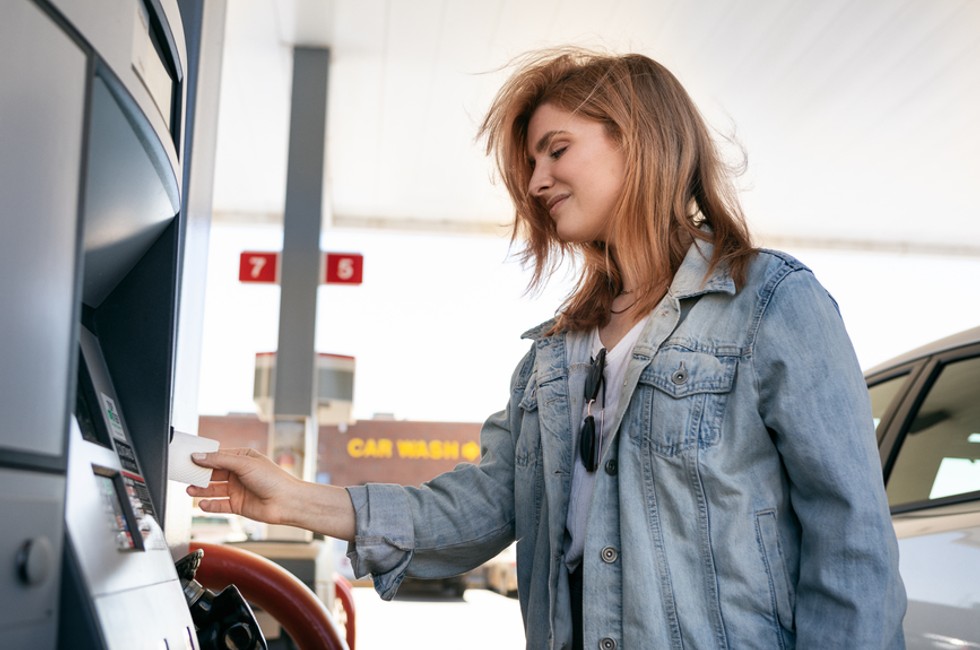 An employee using Payhawk's business mileage reimbursement features by swiping our corporate card at a gas station. 