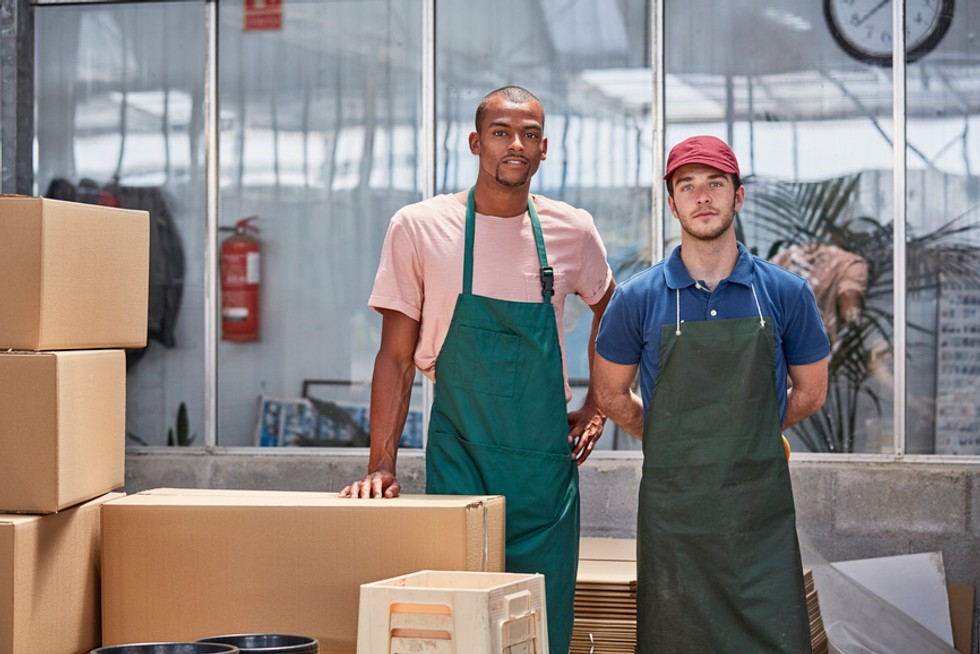 Collega's poseren voor een foto terwijl ze werken aan hun exact erp systeem in de fabriek