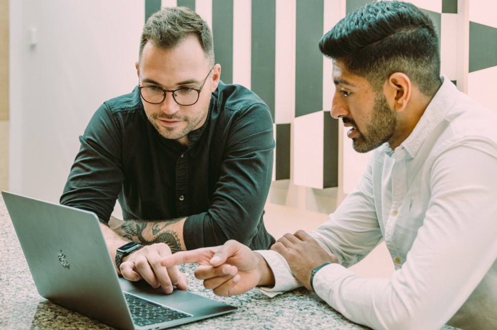 Two male employees working within the Payhawk's bank reconciliation software