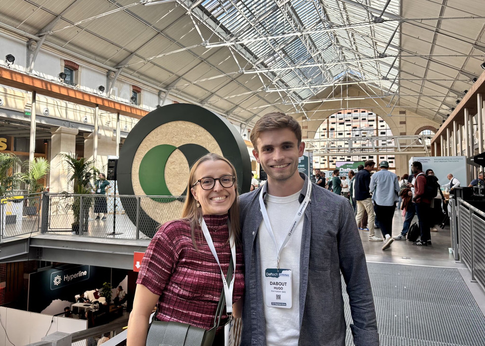 Two members of the Payhawk Partner team at DafTech 2026 at Le 104 in Paris, smiling in front of the Pennylane logo