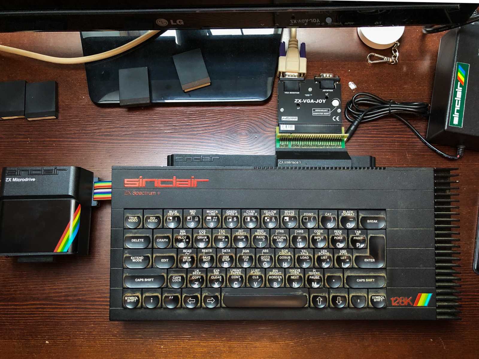 ZX Spectrum 128k – zde je vidět, že Interface 1 pro tento mnohem širší stroj není ideální, neboť jej počítač na obou stranách značně překračuje, nicméně, vše funguje stejně, jako s původním gumákem.