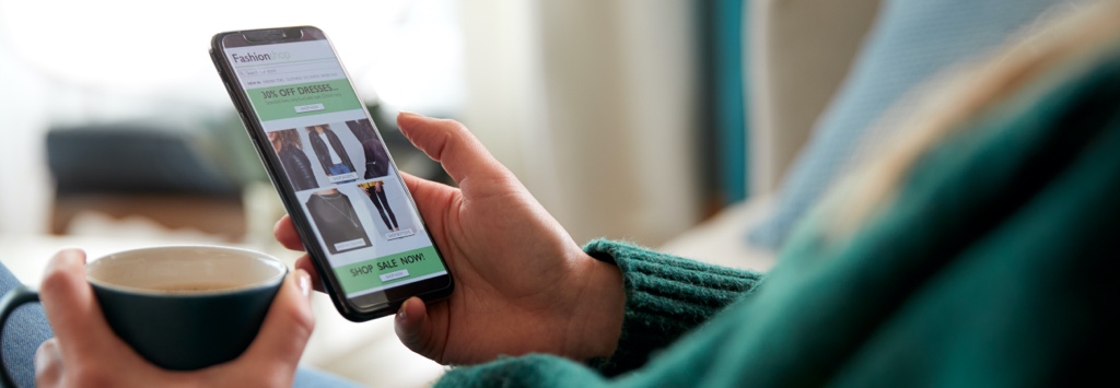 Close up of woman drinking coffee and browsing eCommerce website on mobile phone