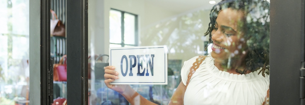 Happy woman turning the open sign at her pop up store