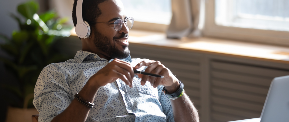 Happy young Black man sitting back in his chair looking at his computer