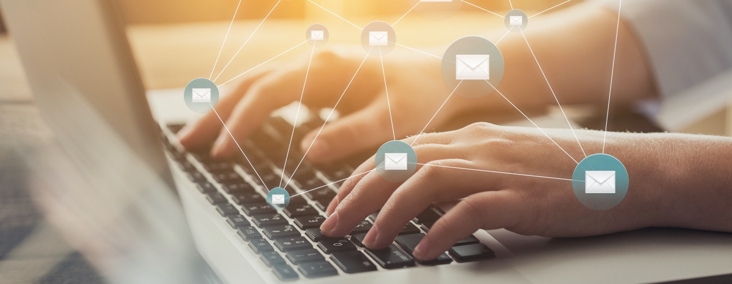 Close up of hands typing on laptop with emails icons floating above hands