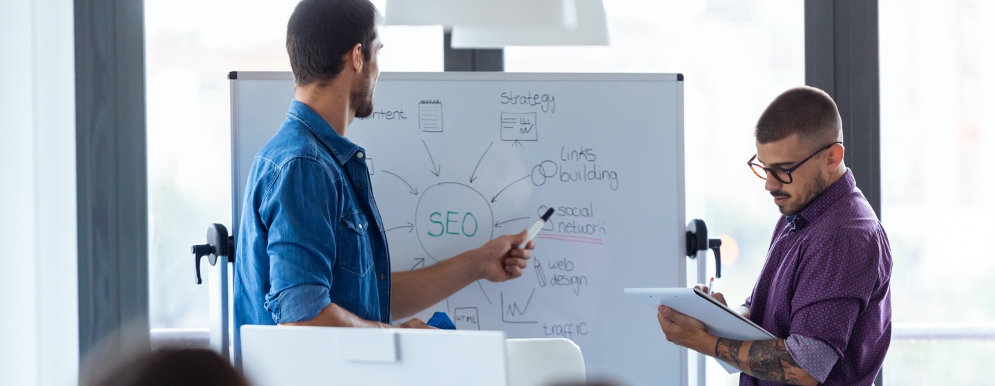 Two men reviewing SEO strategy on a whiteboard