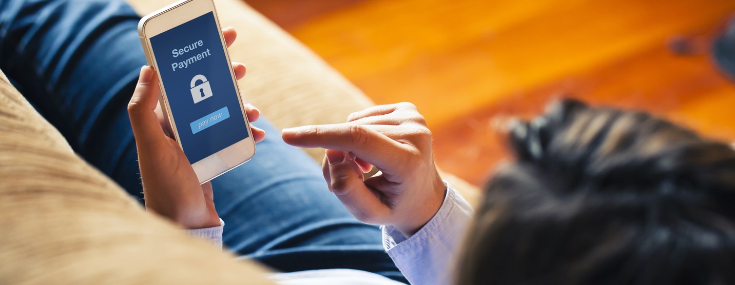 Man submitting a secure payment on his mobile phone while laying on a couch