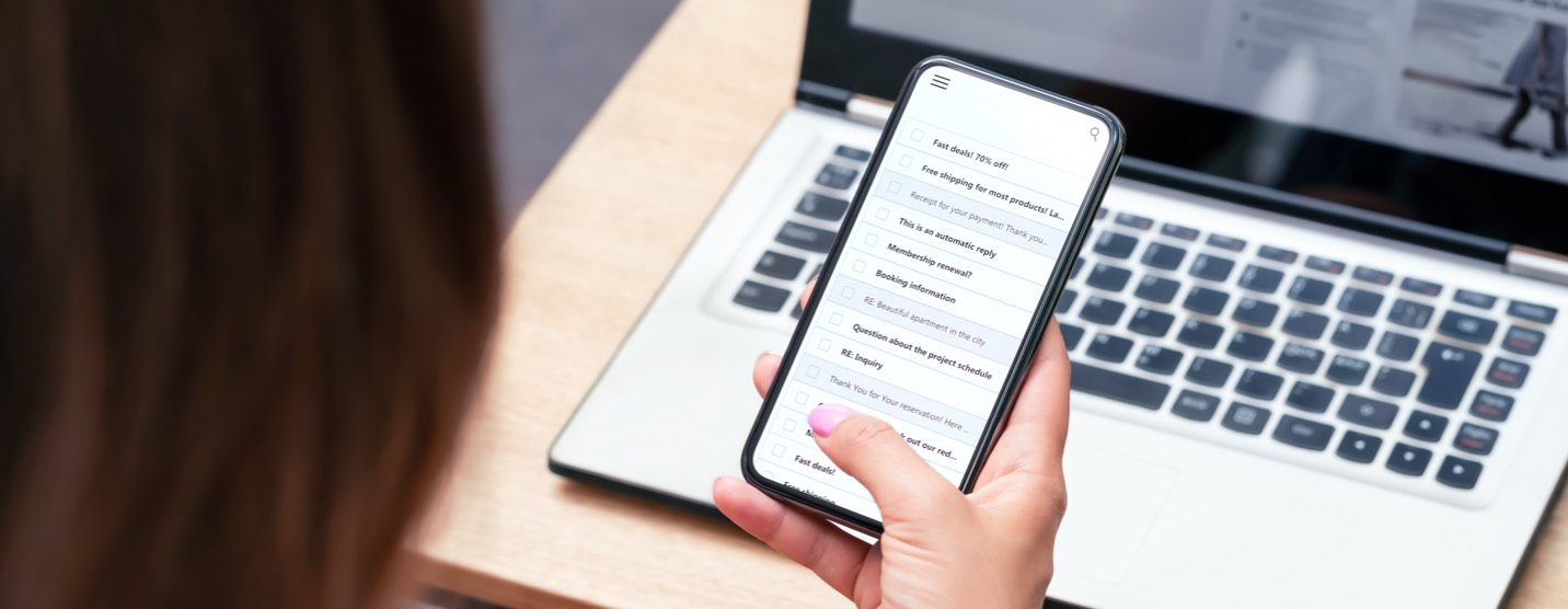 Young woman sitting at a table browsing her emails on a smart phone